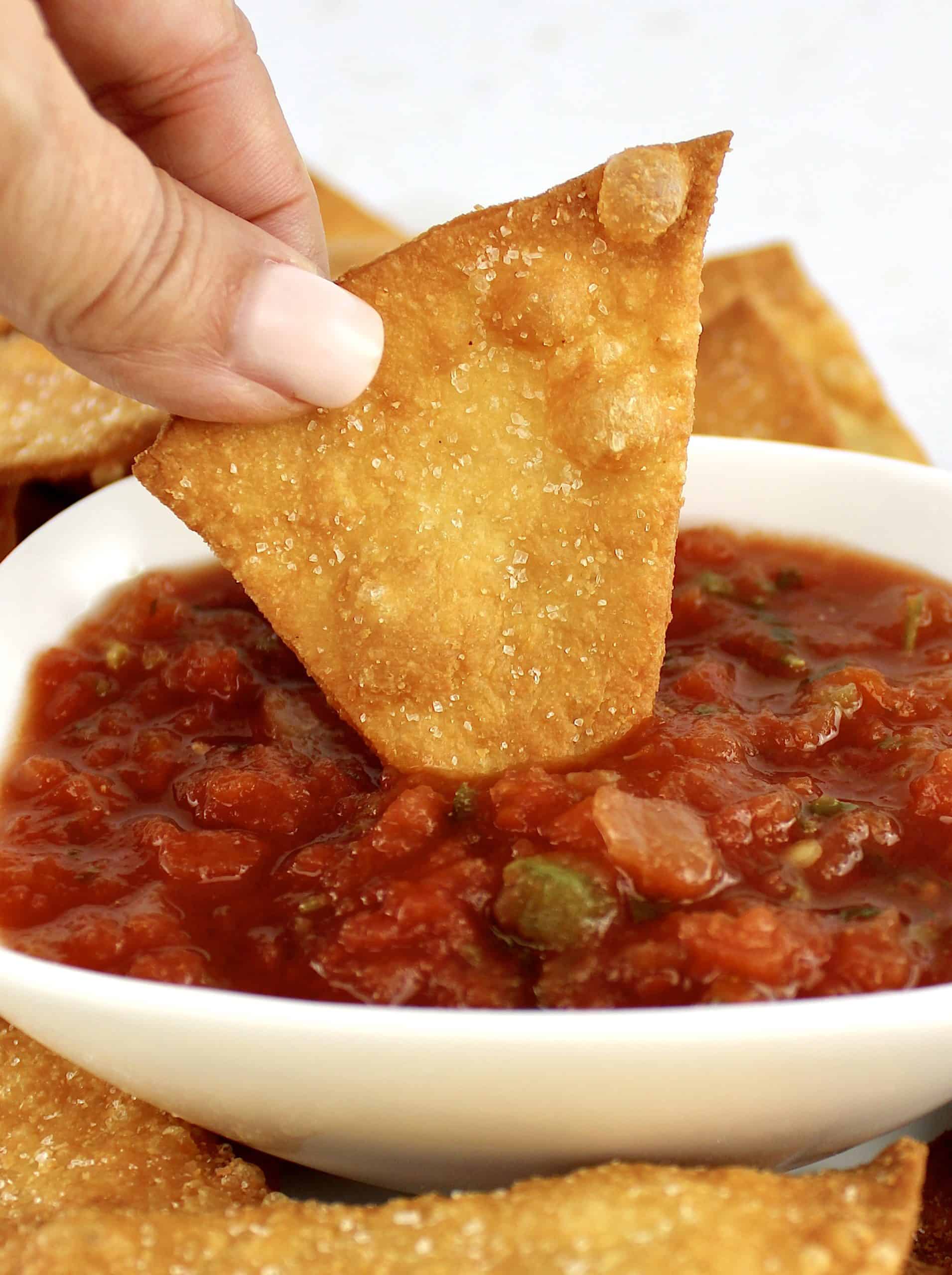 Keto Tortilla Chip being dipped into salsa in white bowl