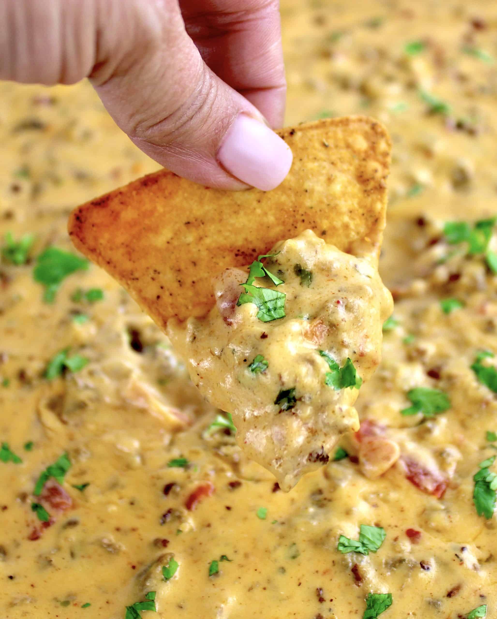 tortilla chip being dipping into Sausage Rotel Dip