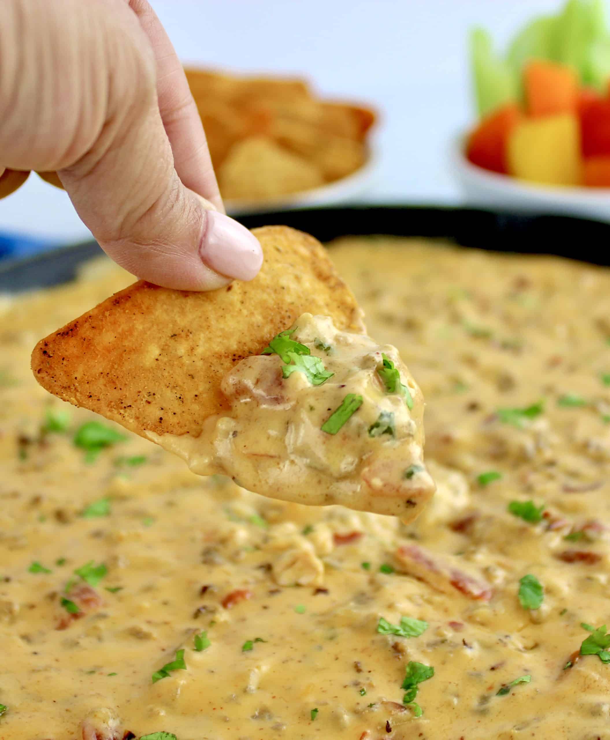 tortilla chip being dipped into Sausage Rotel Dip