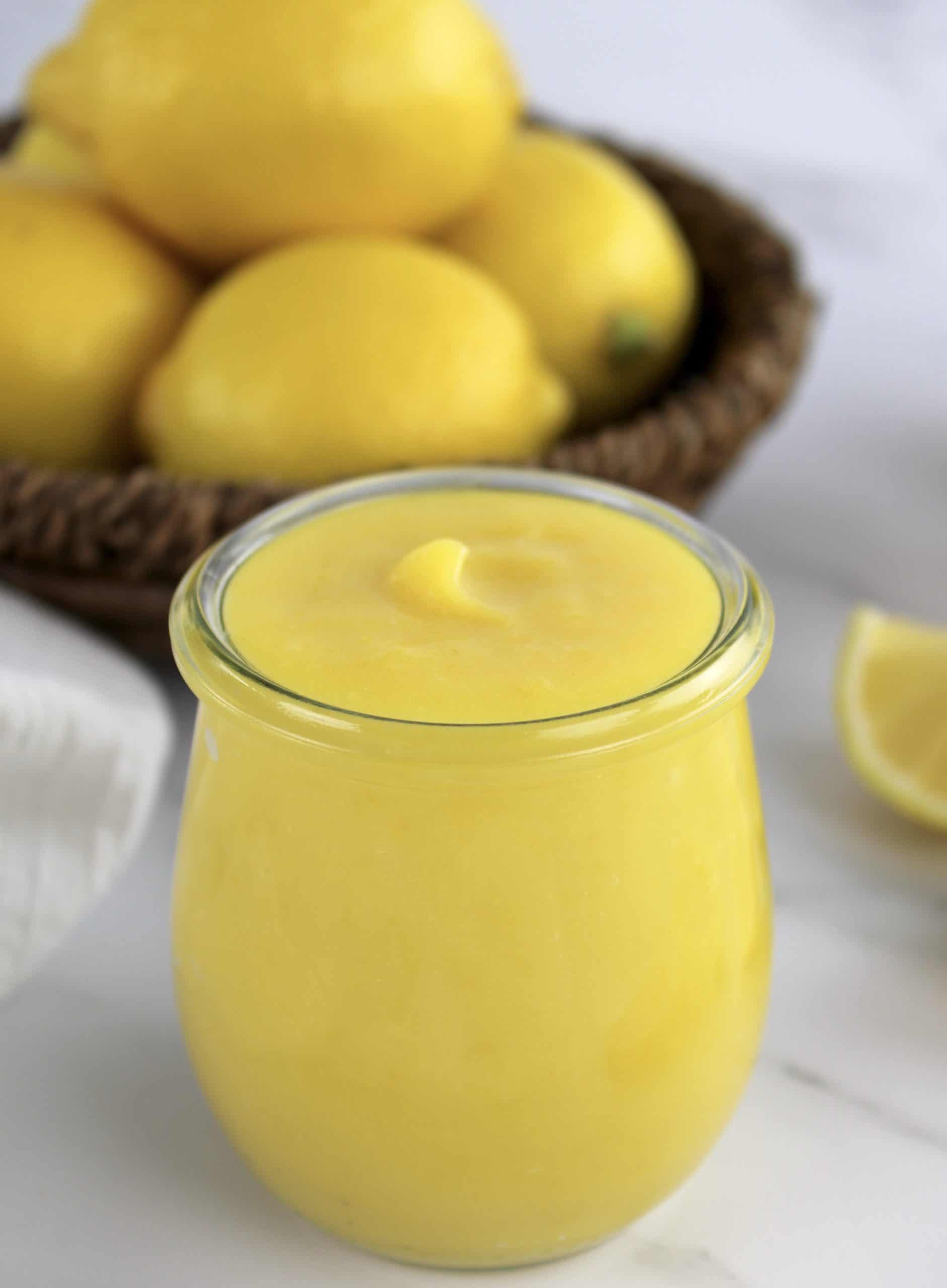 5 Minute Keto Lemon Curd in open glass jar with lemons in background