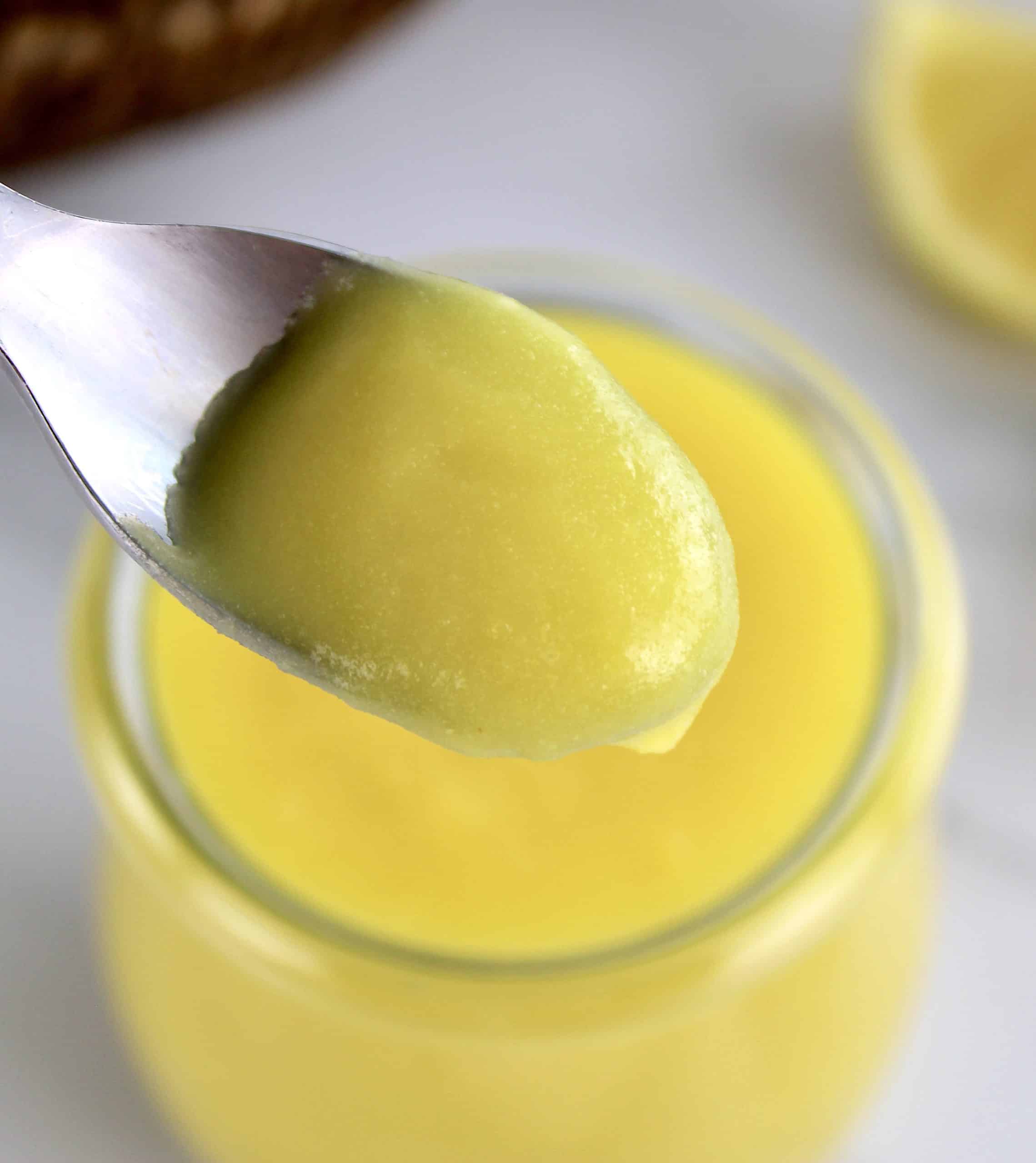 closeup of lemon curd in spoon over jar