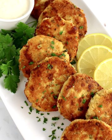 chicken patties with lemon slices on white plate with parsley garnish