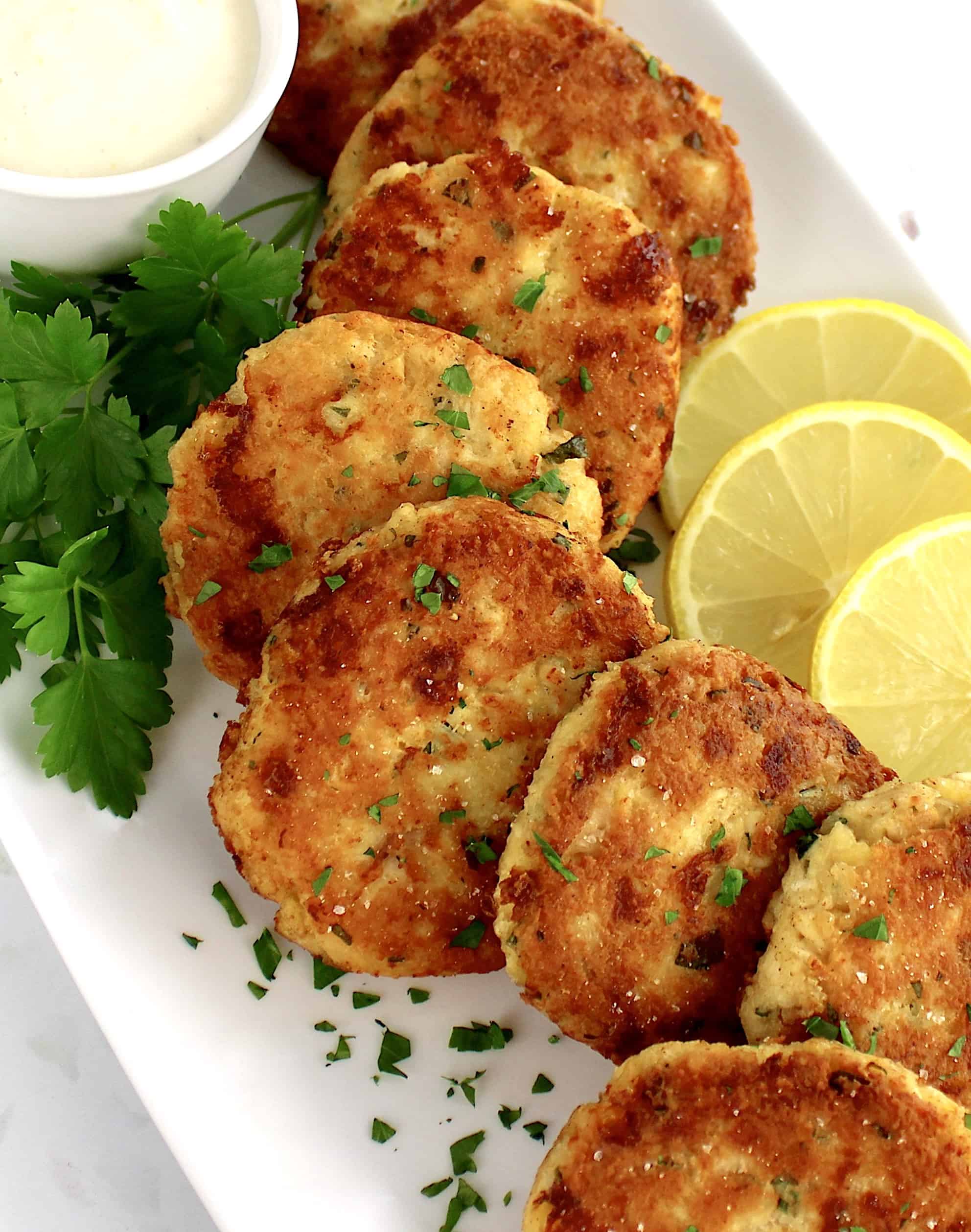 chicken patties with lemon slices on white plate with parsley garnish