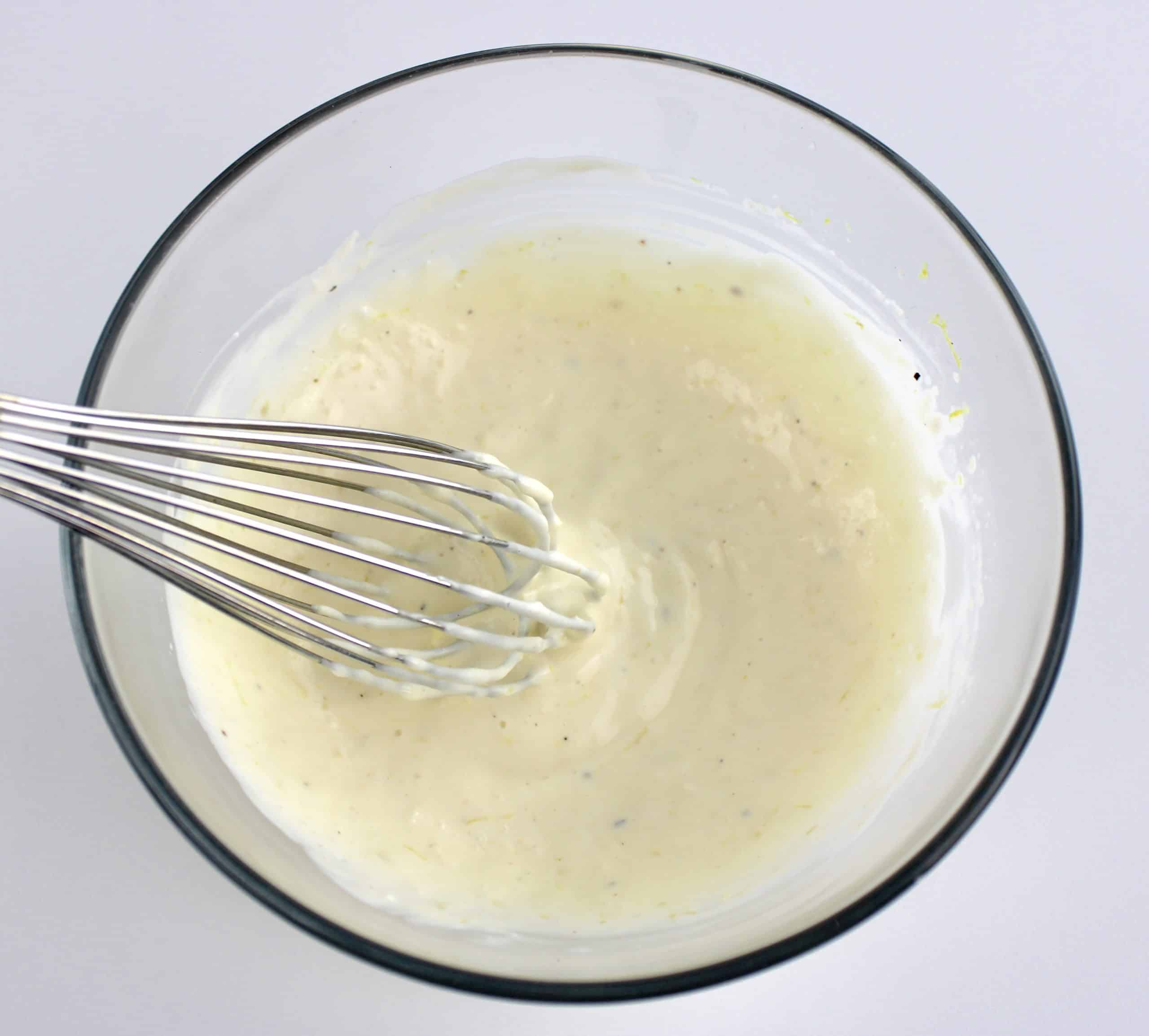 garlic aioli in glass bowl with whisk