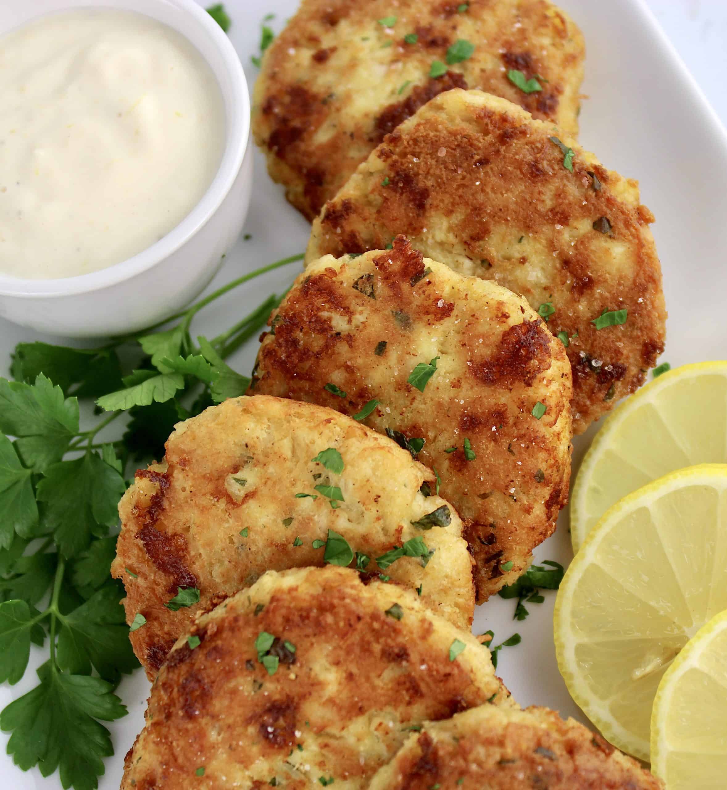 chicken patties with lemon slices on white plate with parsley garnish