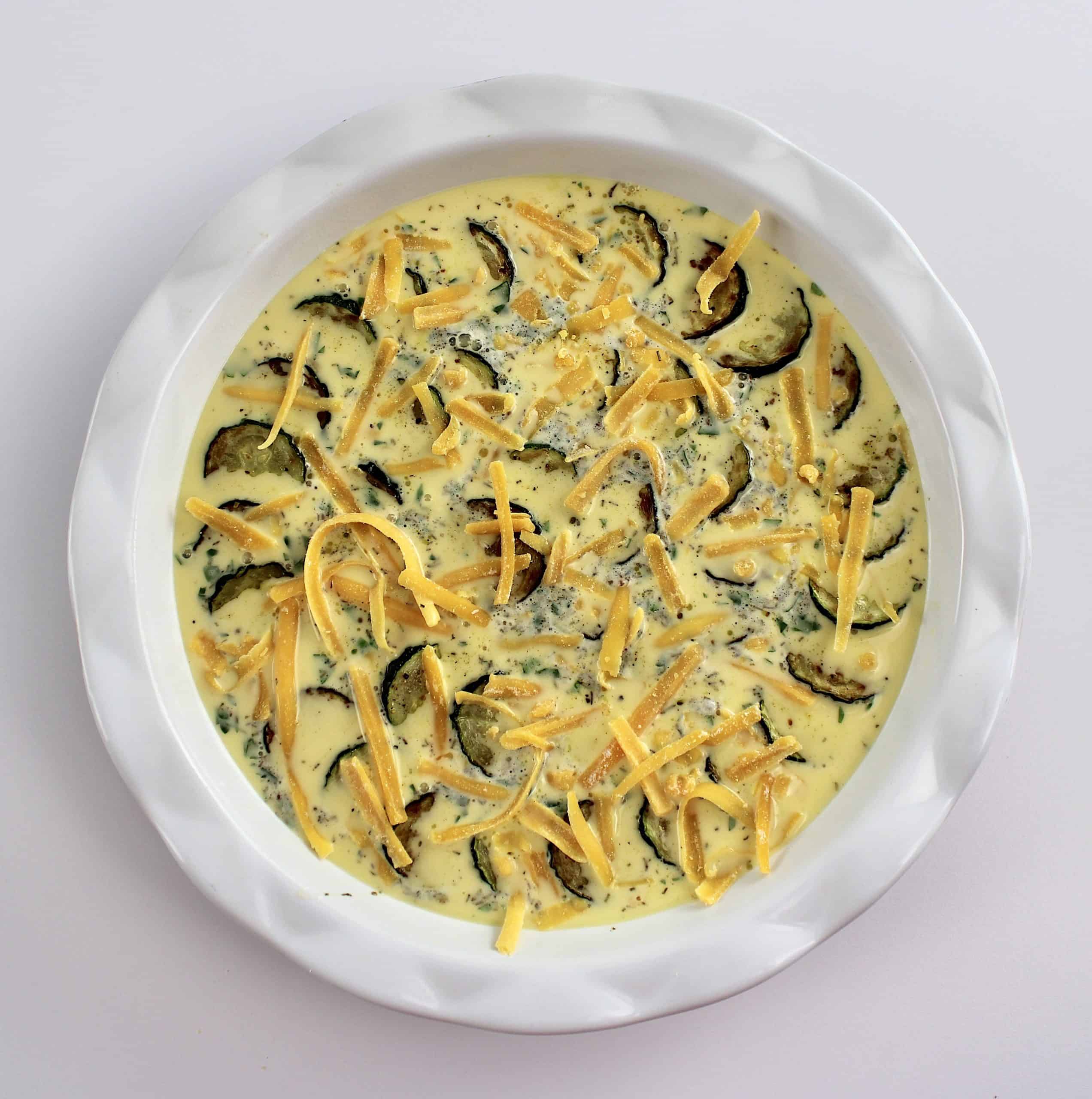 cheddar and zucchini crustless quiche in pie dish unbaked