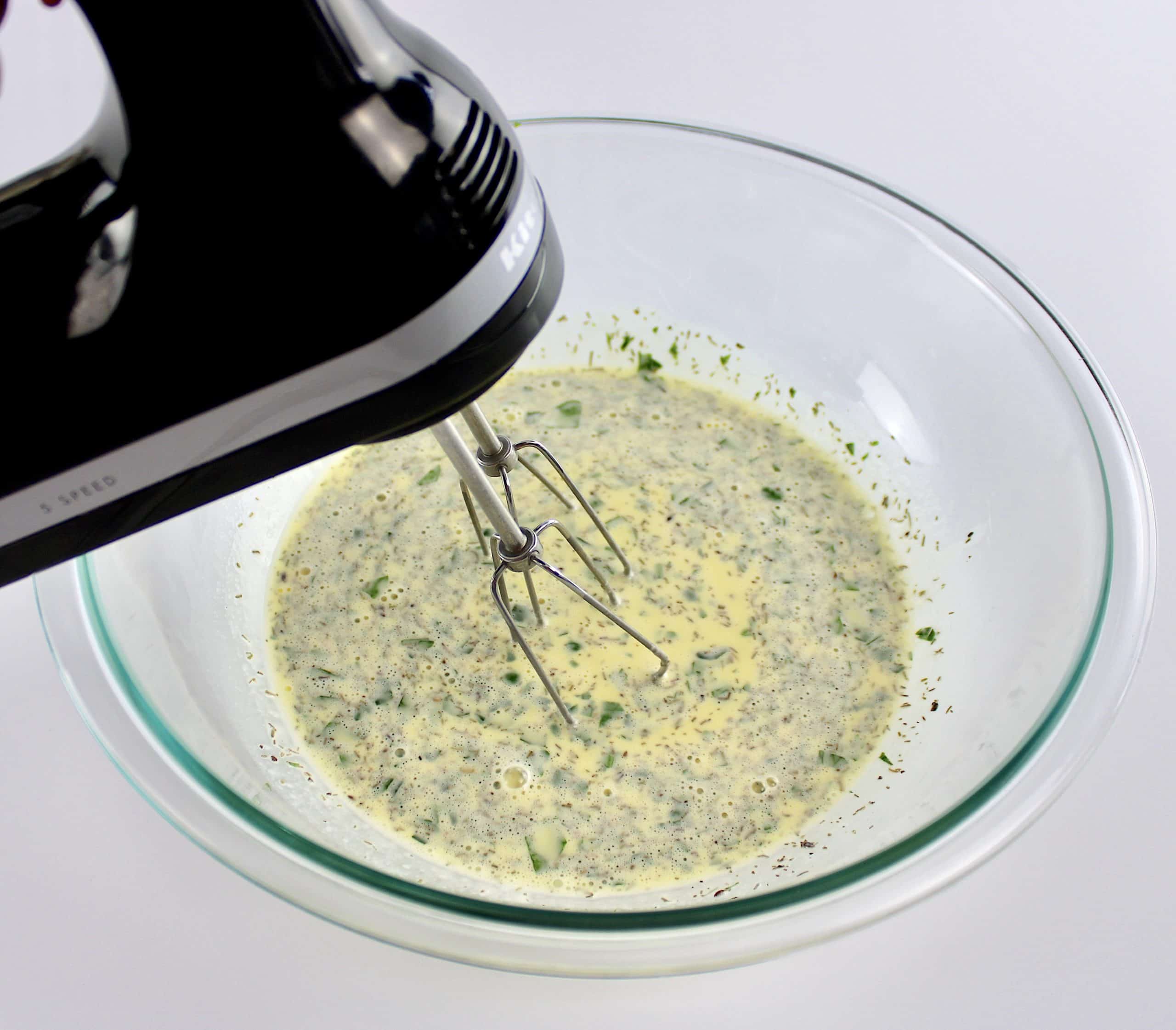 eggs with herbs and cream being mixed with hand mixer