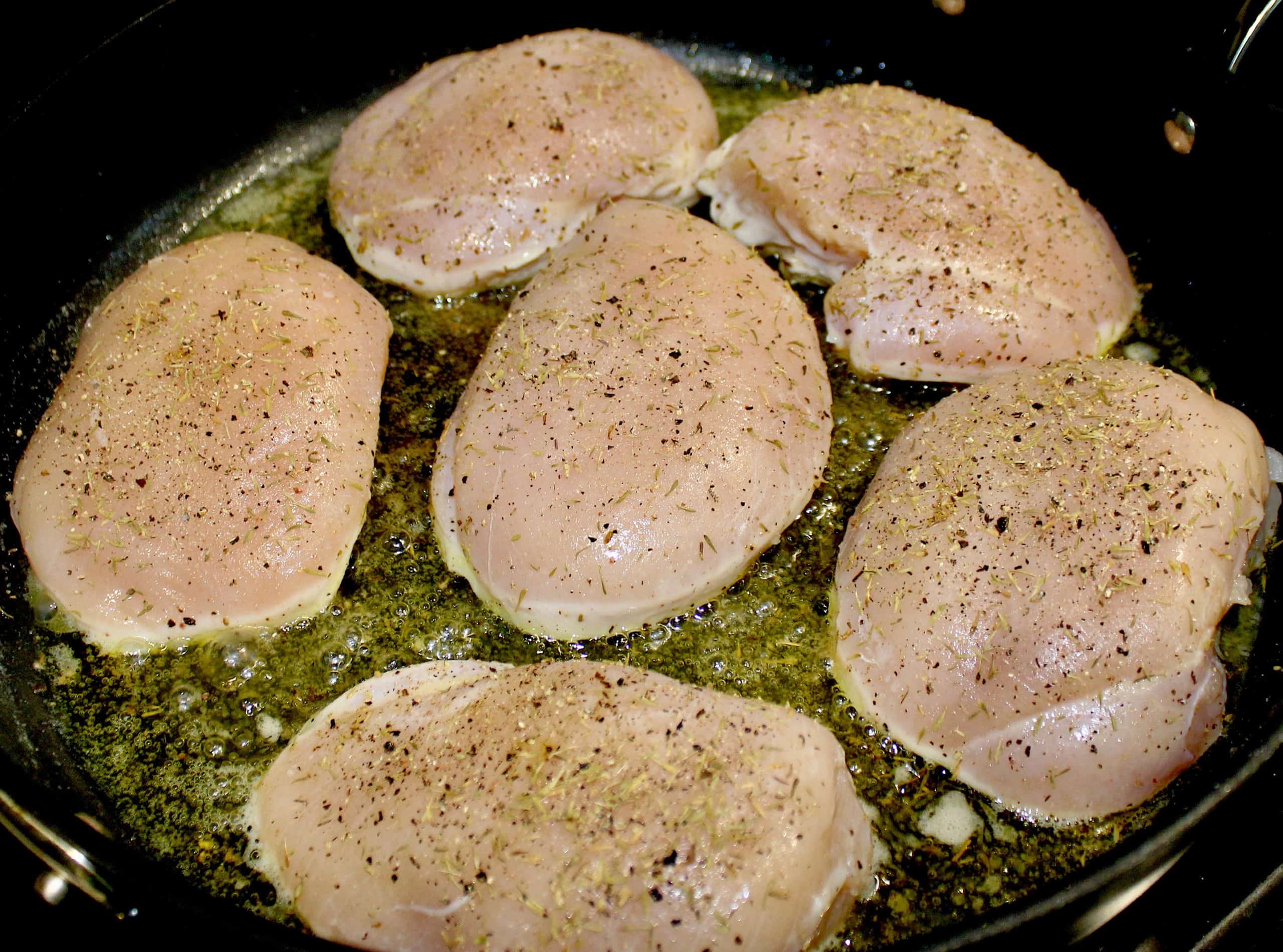 6 pieces of chicken with spices cooking in skillet