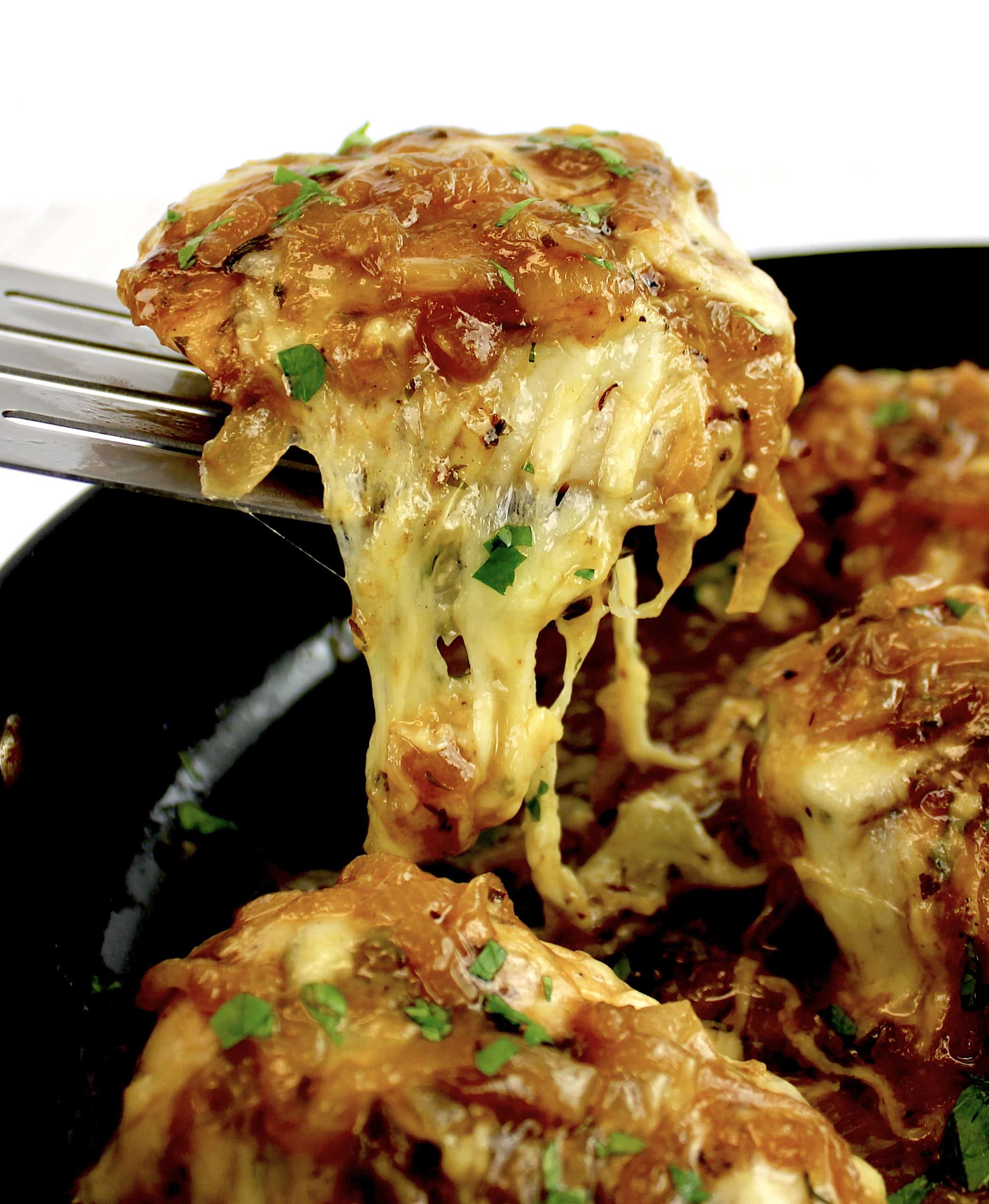 piece of French Onion Chicken being held up with spatula with cheese pull