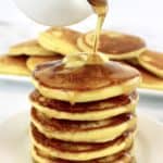 stack of pancakes with butter on top and maple syrup being poured on top