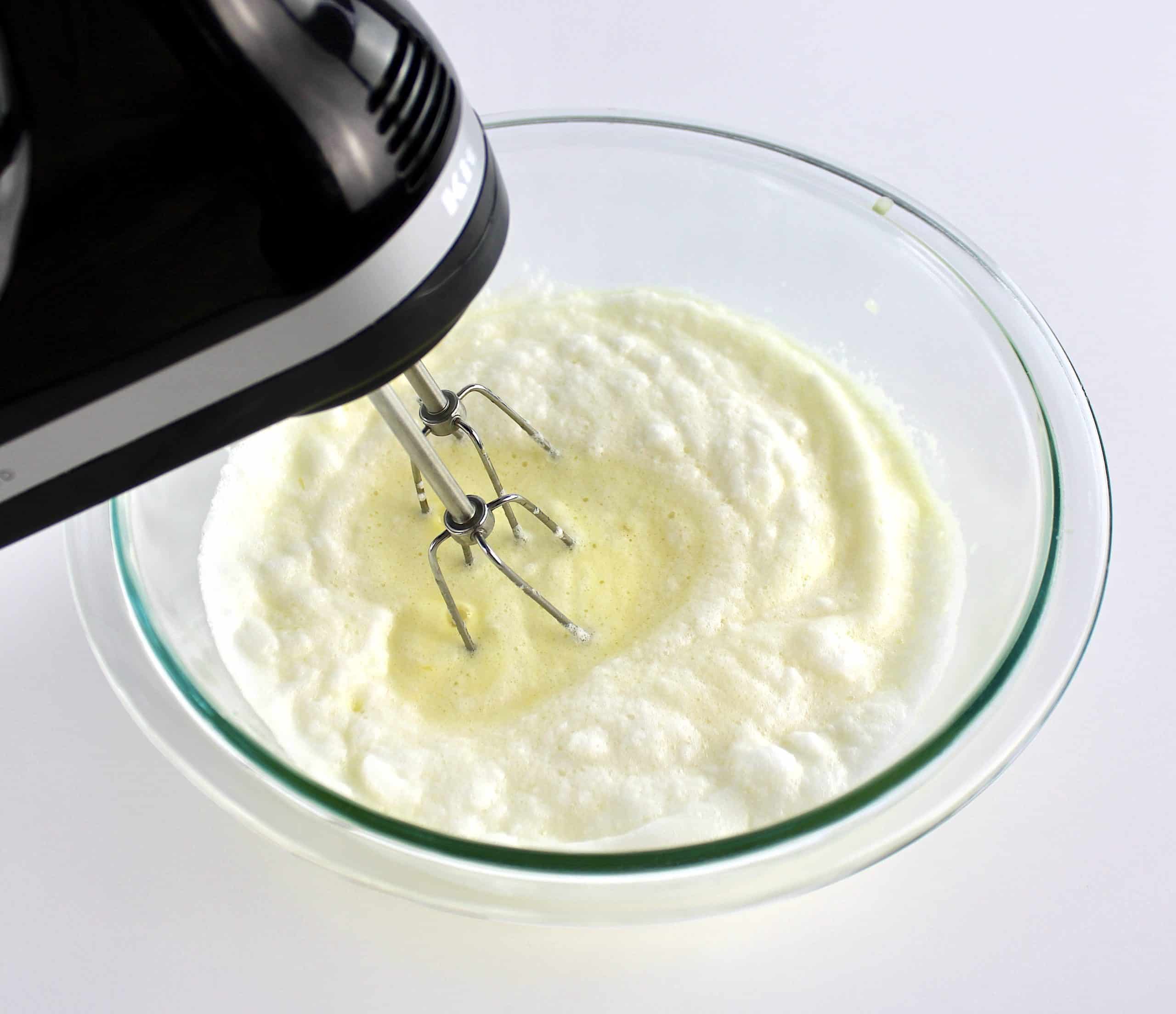 egg yolks being whipped into egg whites with hand mixer 