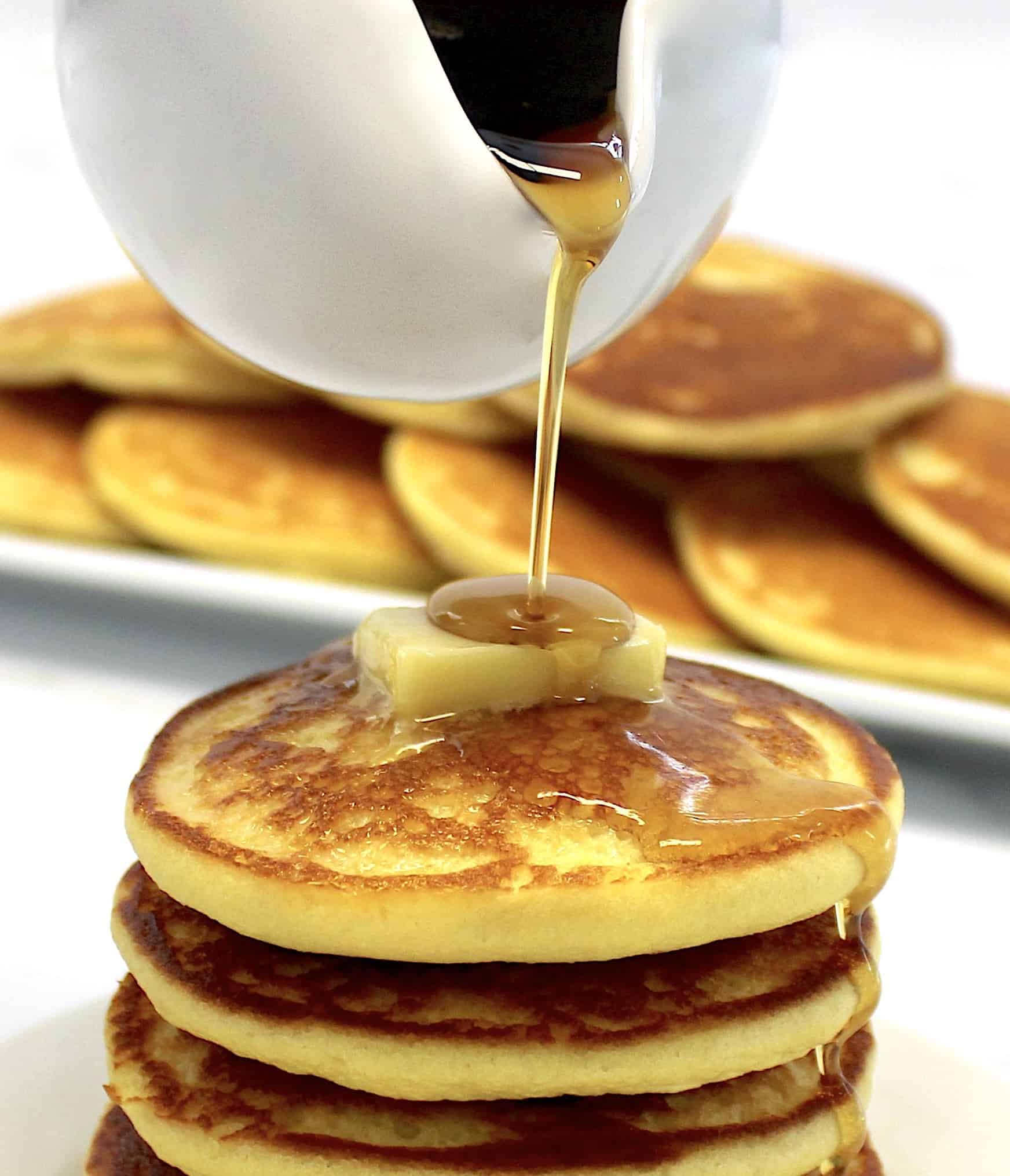 Keto Buttermilk Pancakes with butter on top and maple syrup being poured on top