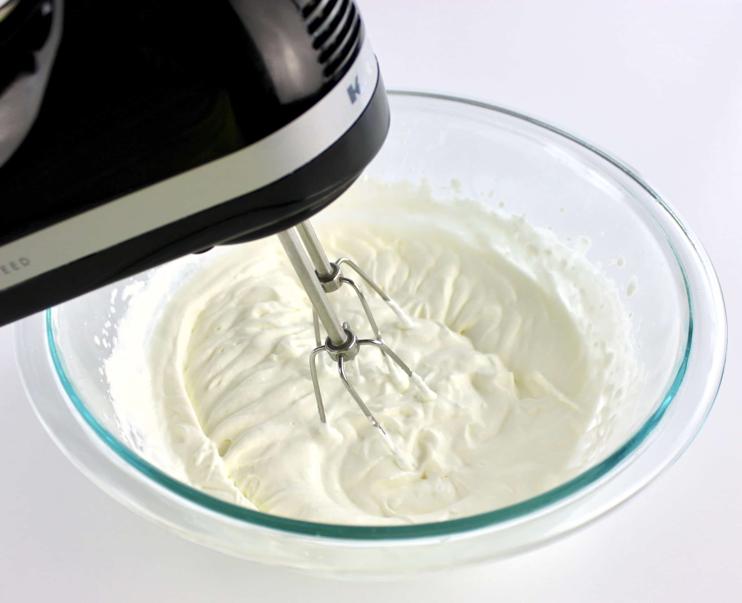 whip cream in glass bowl with hand mixer