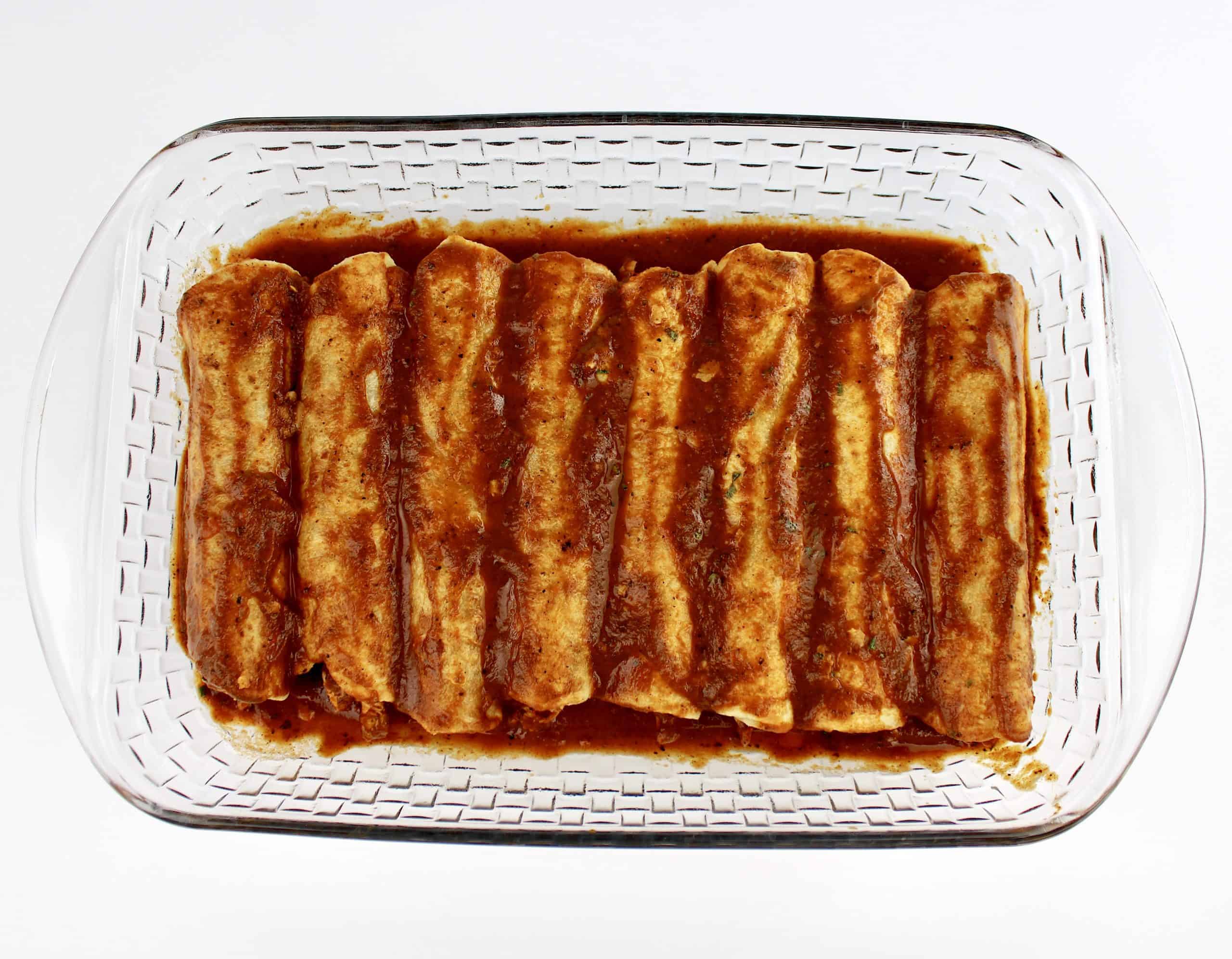 8 Chicken Enchiladas inn glass dish with sauce over the tops