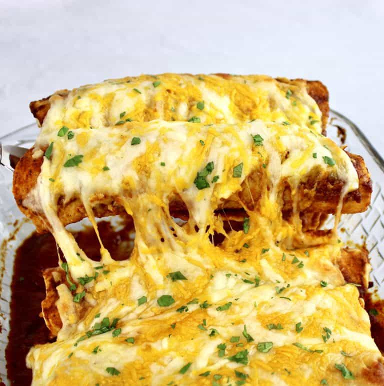 2 Keto Chicken Enchiladas being lifted out of casserole