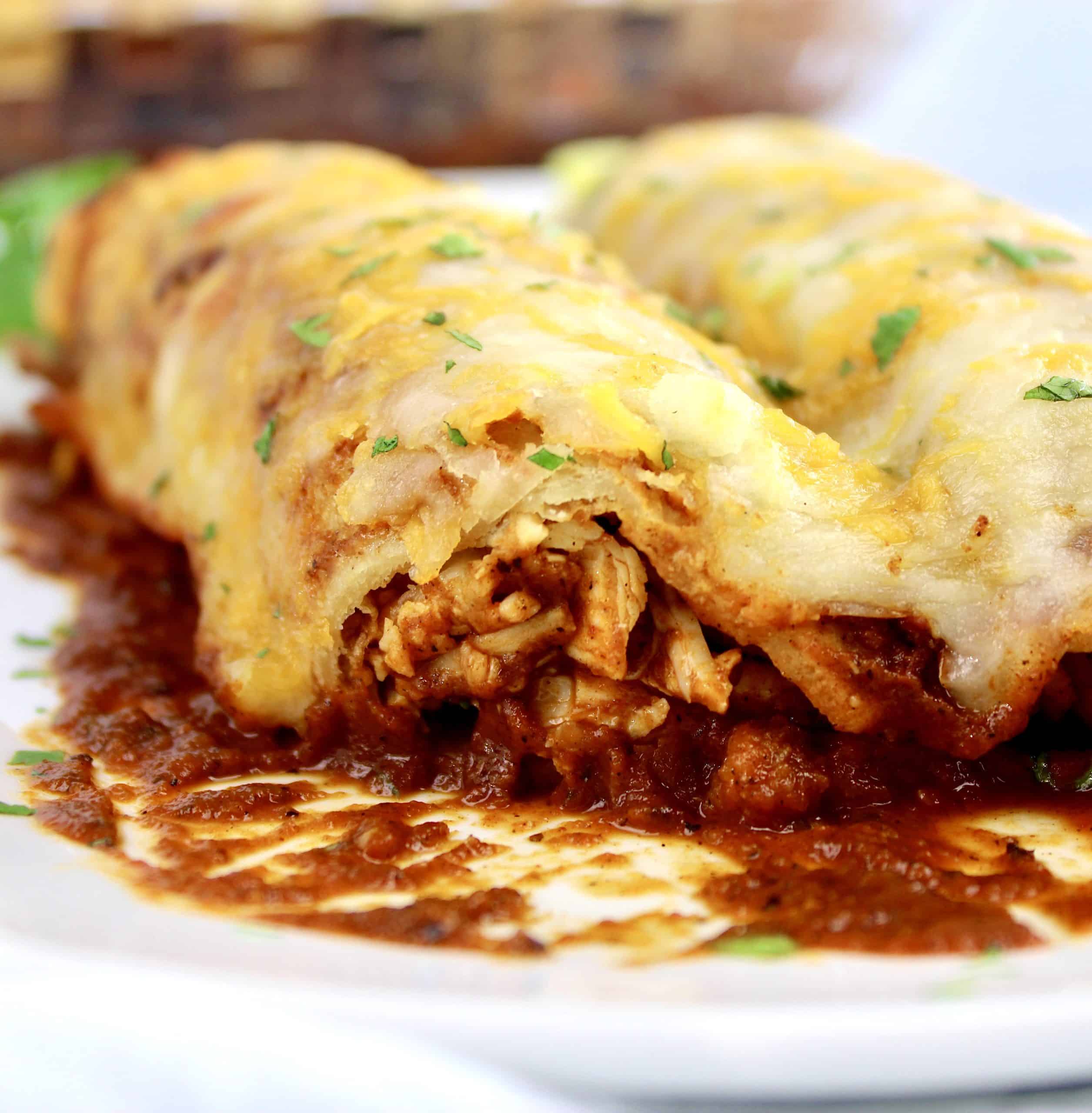 closeup of a chicken enchilada cut open on white plate