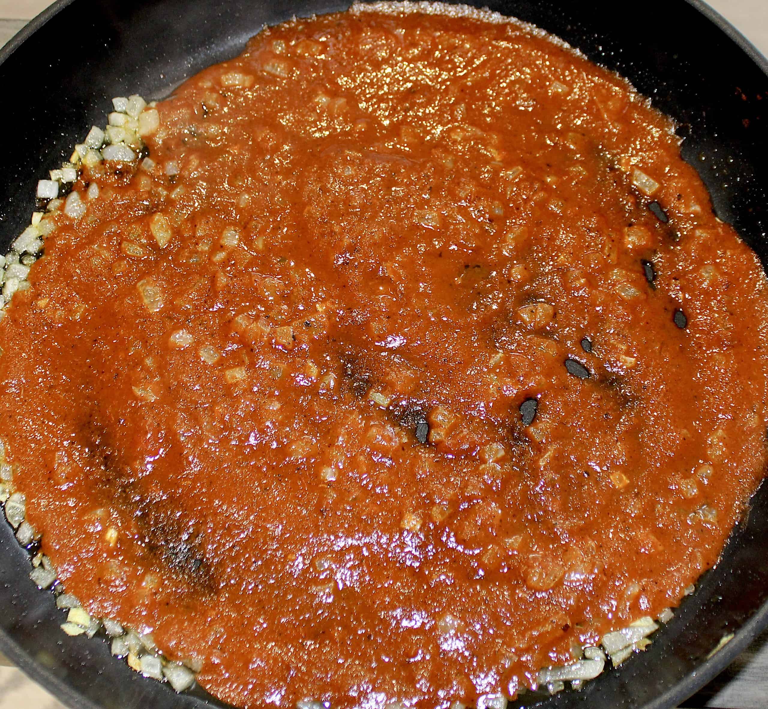enchilada sauce and diced onions in skillet