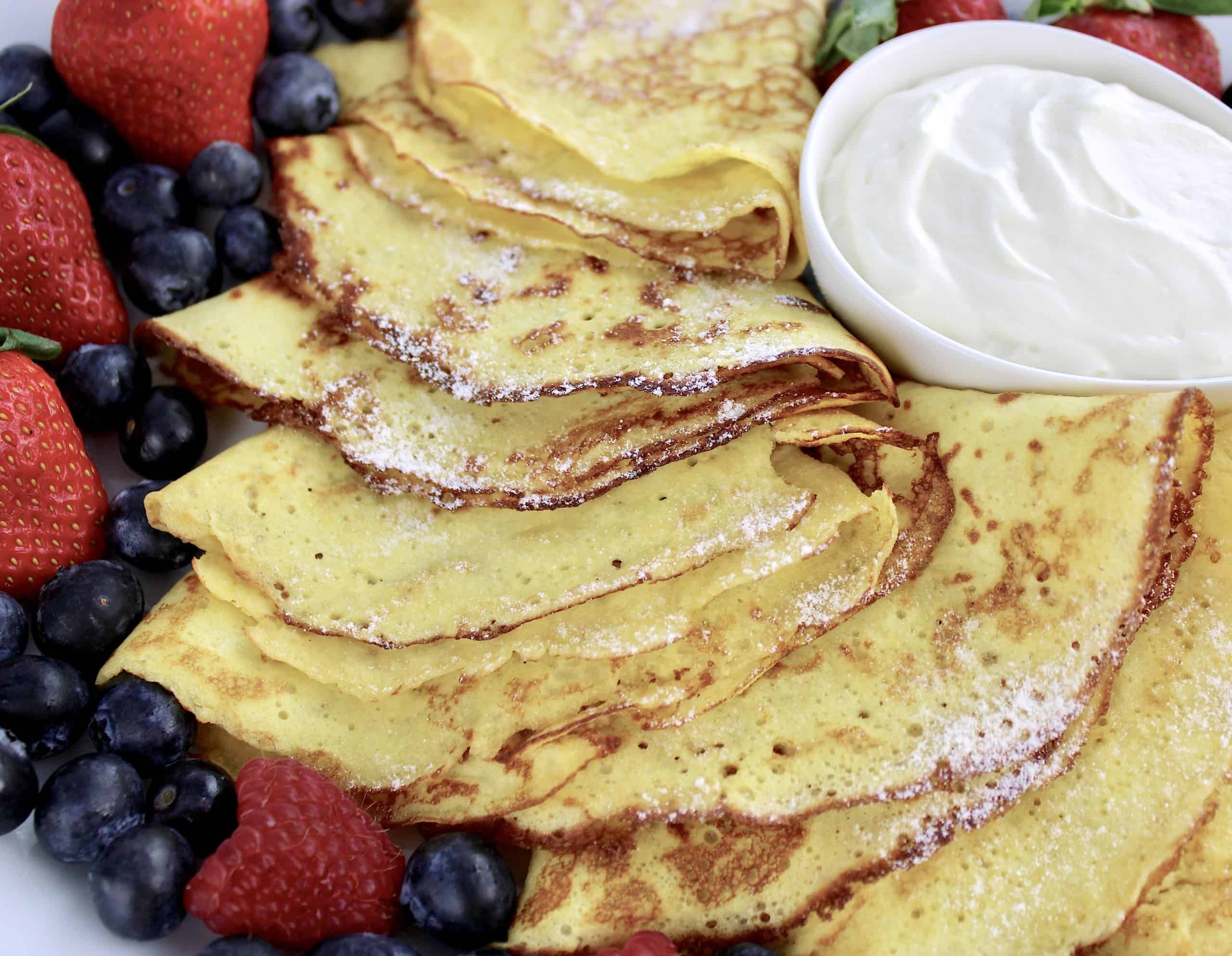 closeup of crepes with berries on white platter