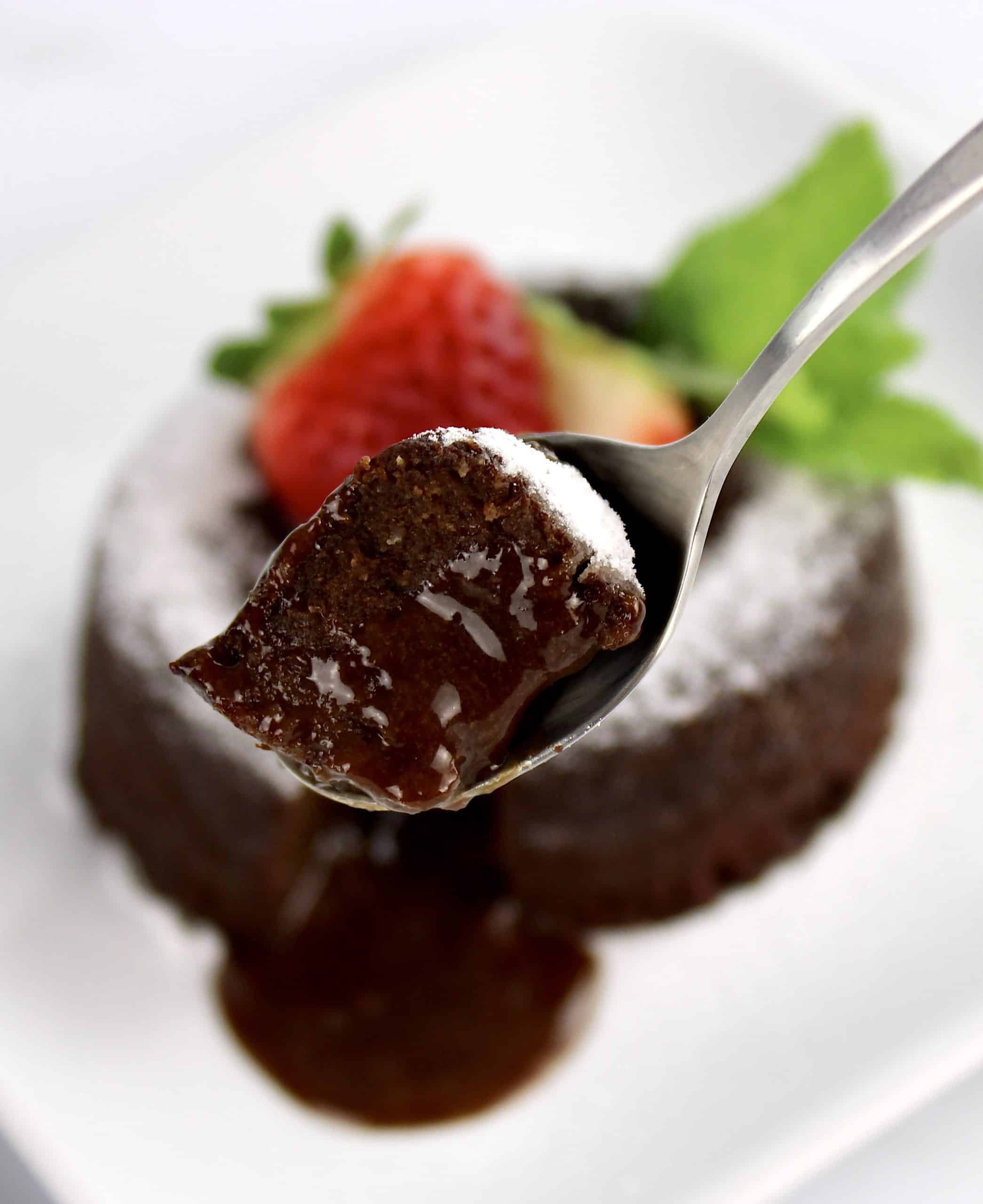 bite of lava cake in spoon with cake in background