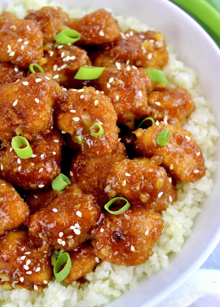 orange chicken over cauliflower rice with scallions on top