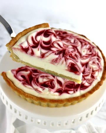 Keto White Chocolate Raspberry Cheesecake with slice being held up with pie server