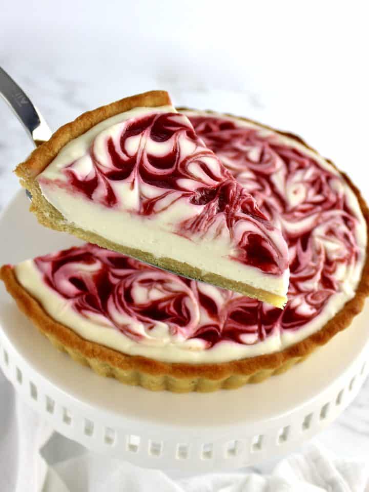Keto White Chocolate Raspberry Cheesecake with slice being held up with pie server