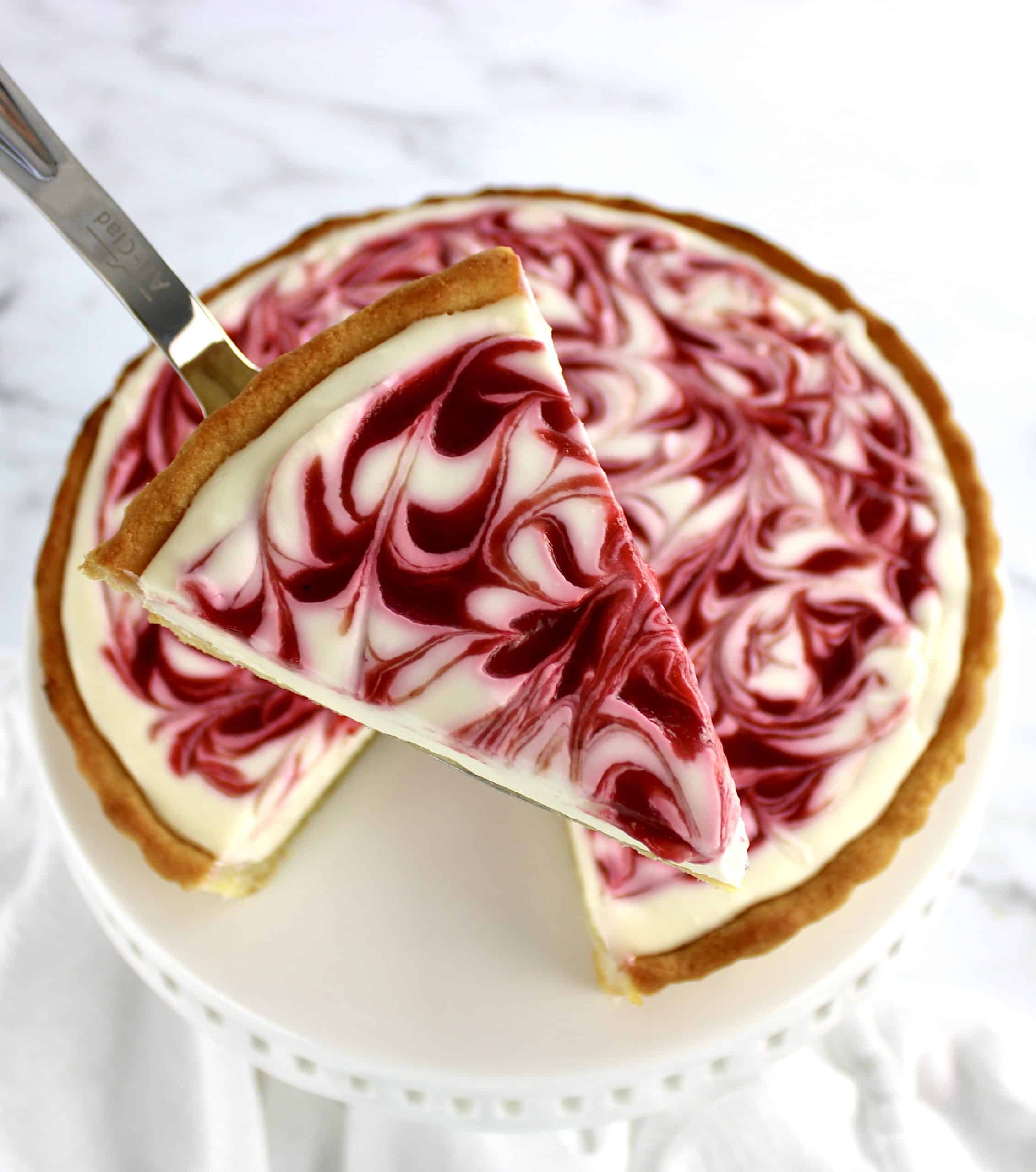 overhead view of Keto White Chocolate Raspberry Cheesecake slice held up with pie server