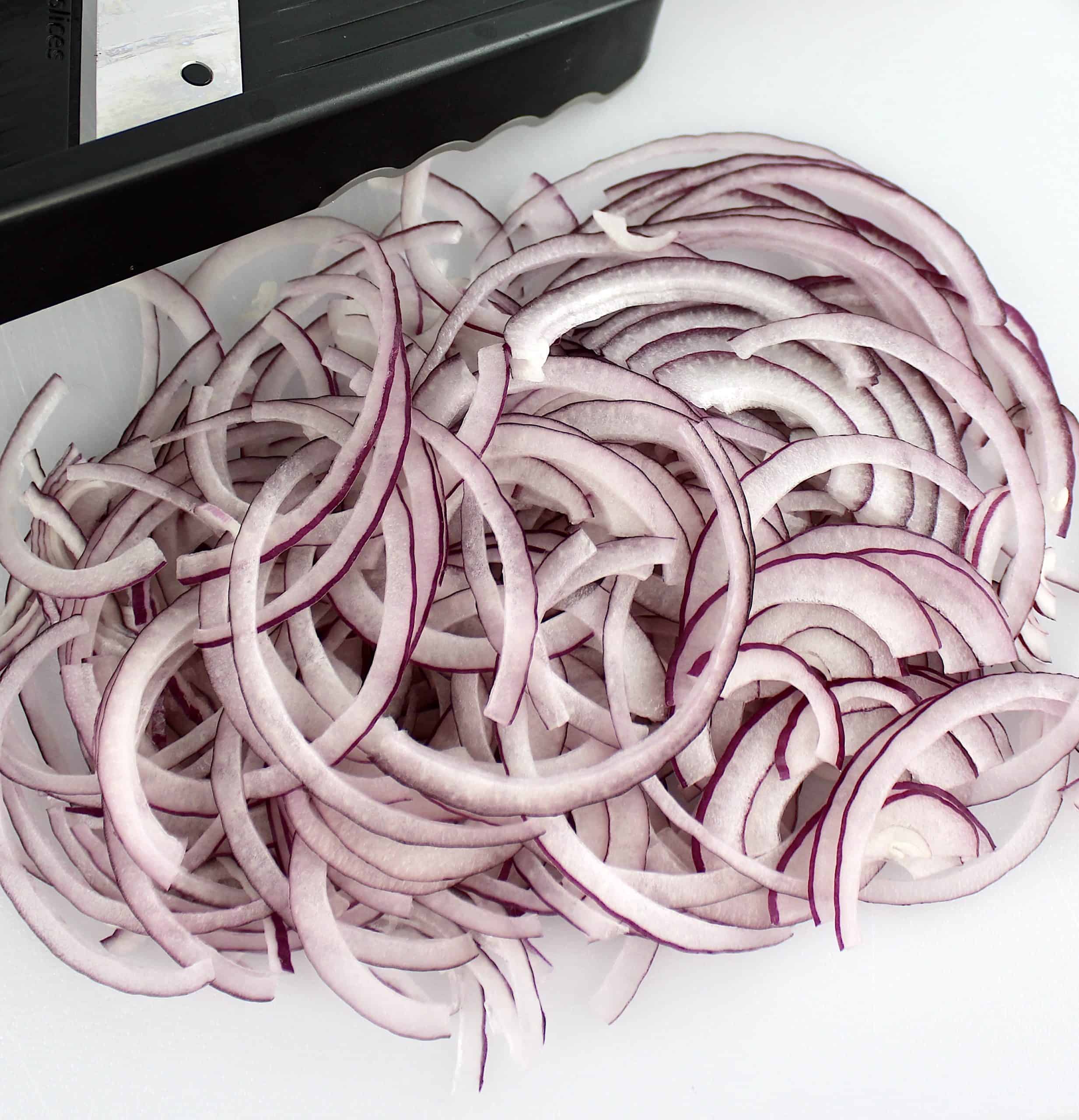 red onion sliced thin on white cutting board