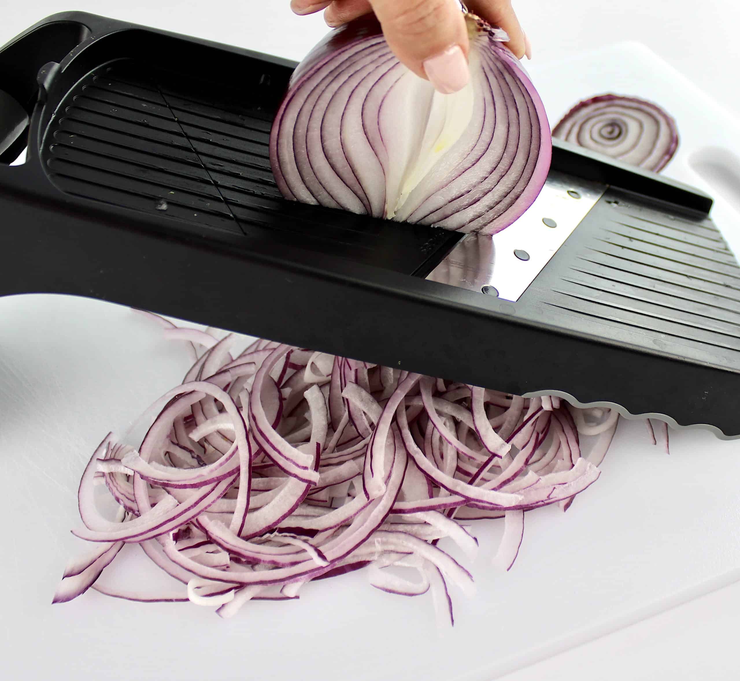 red onion being sliced on madolin