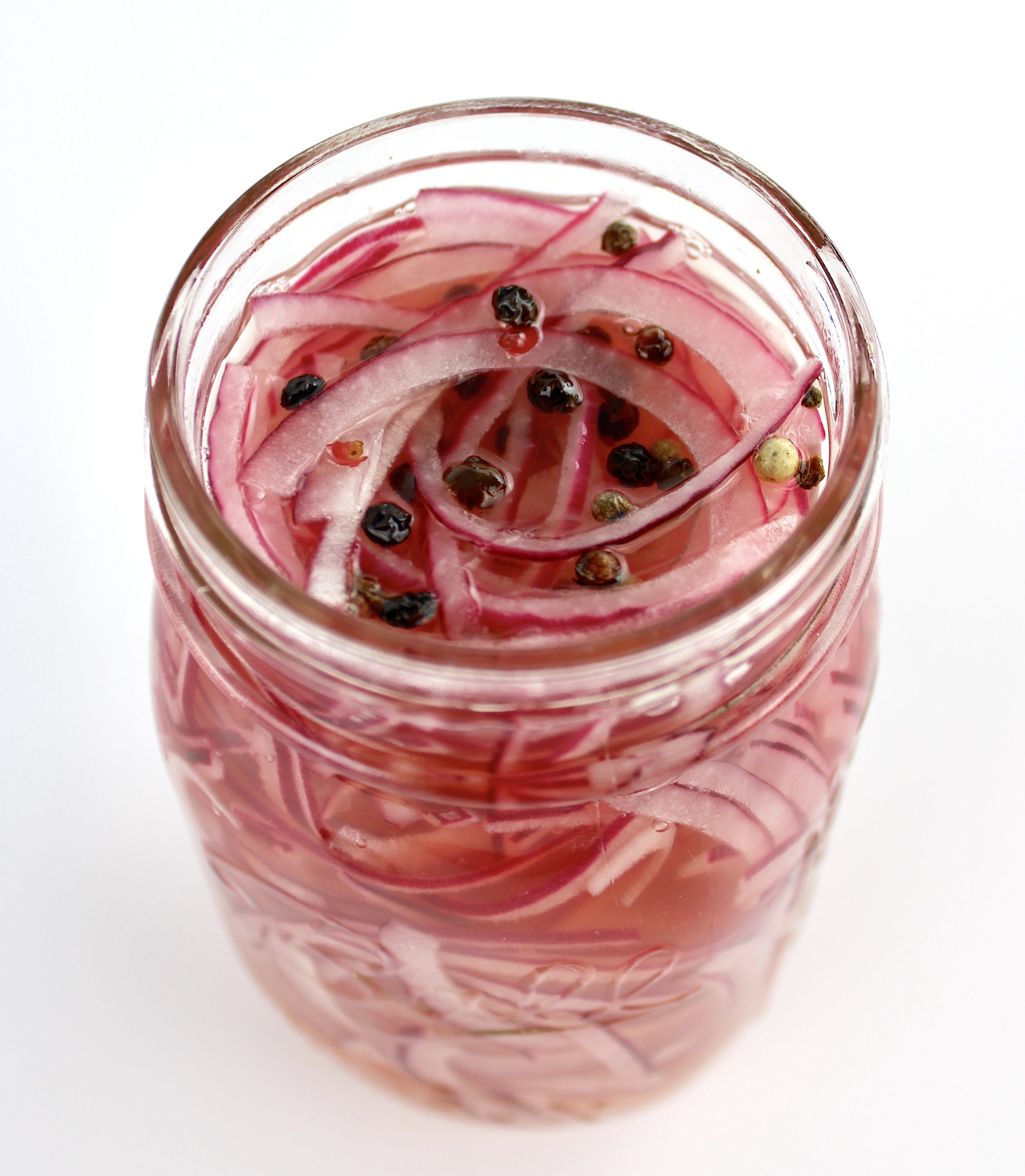 Pickled Red Onions with peppercorns in open mason jar