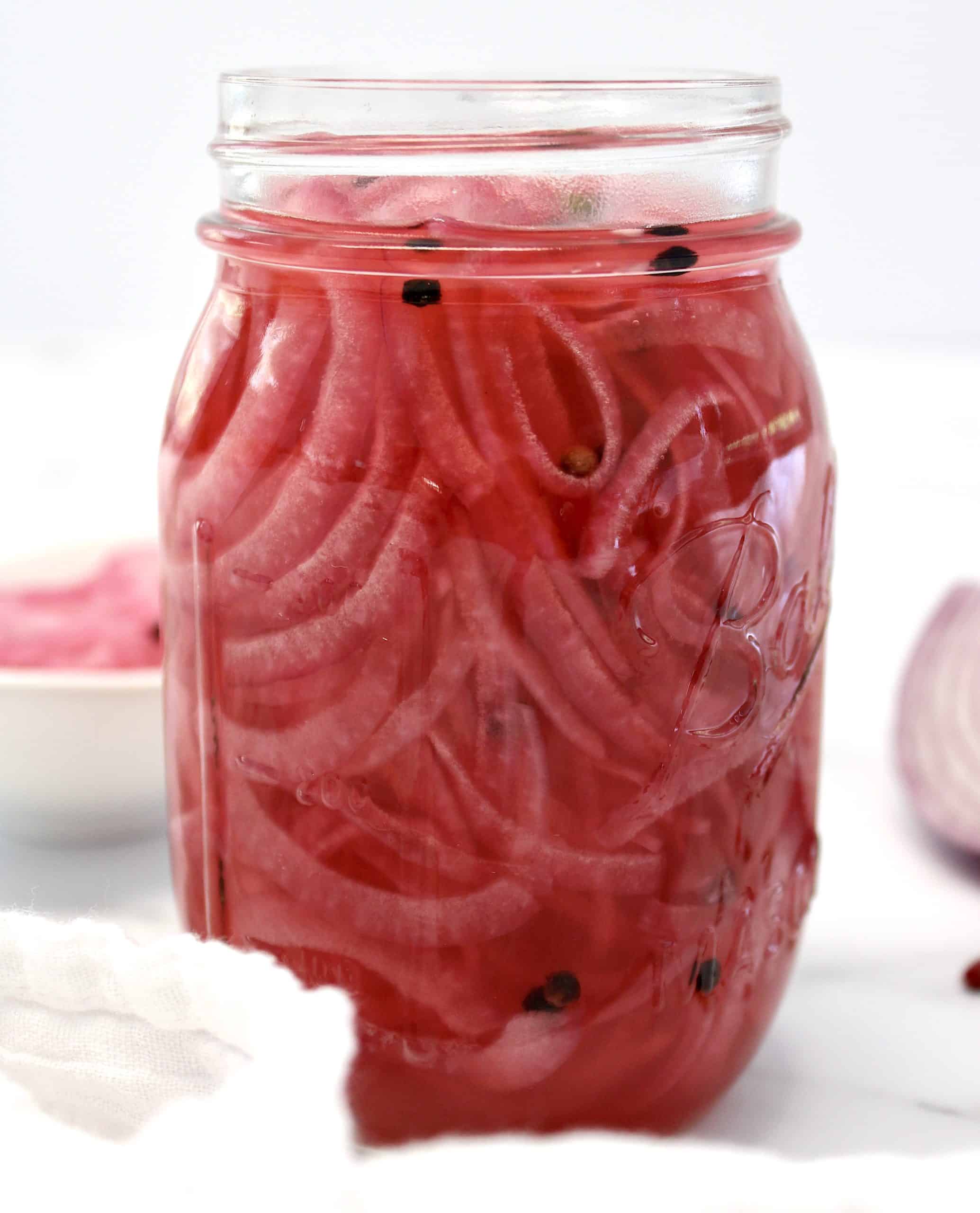 side view of Pickled Red Onions in open mason jar