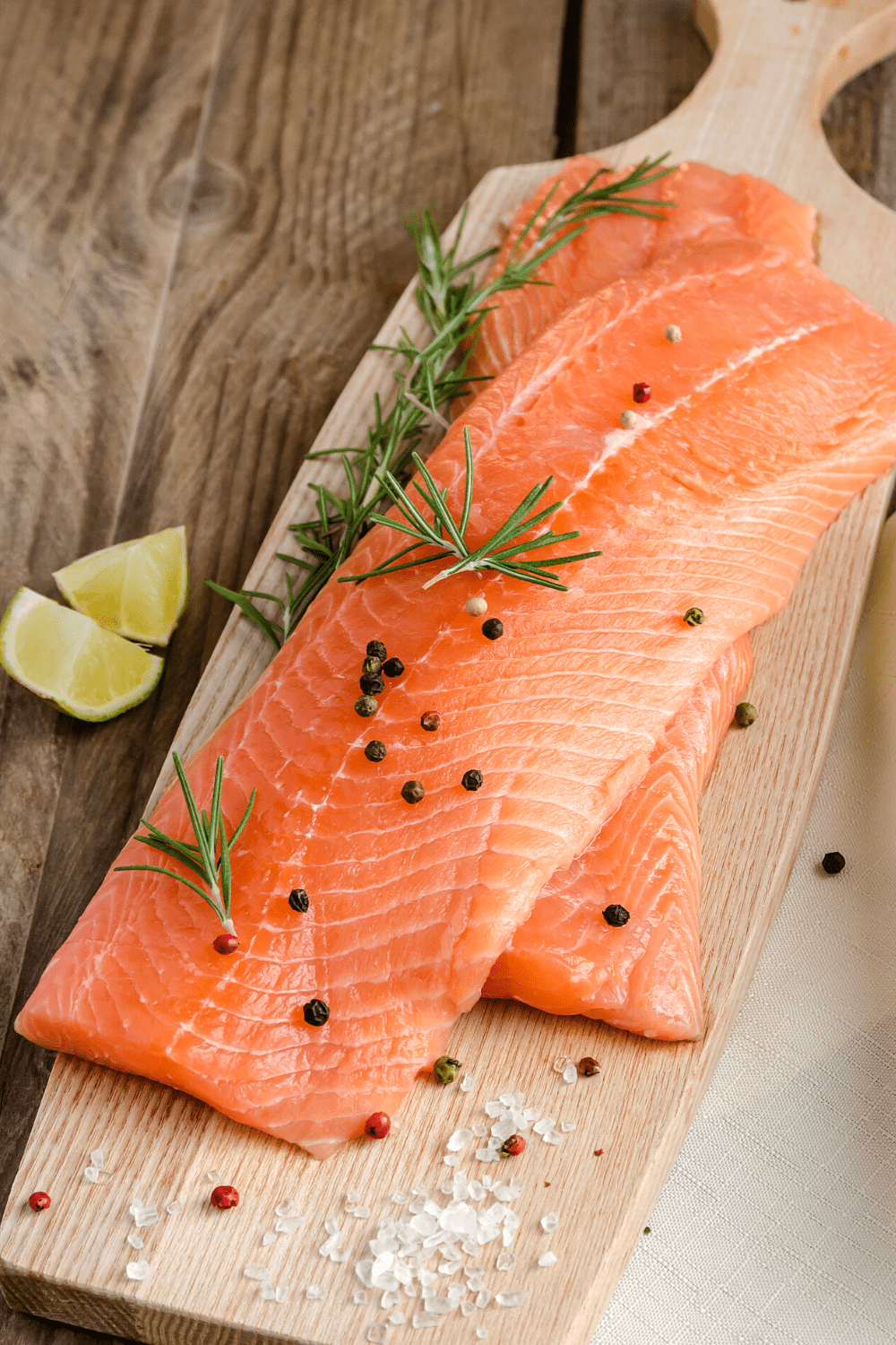 salmon on cutting board with dill and peppercorns on top