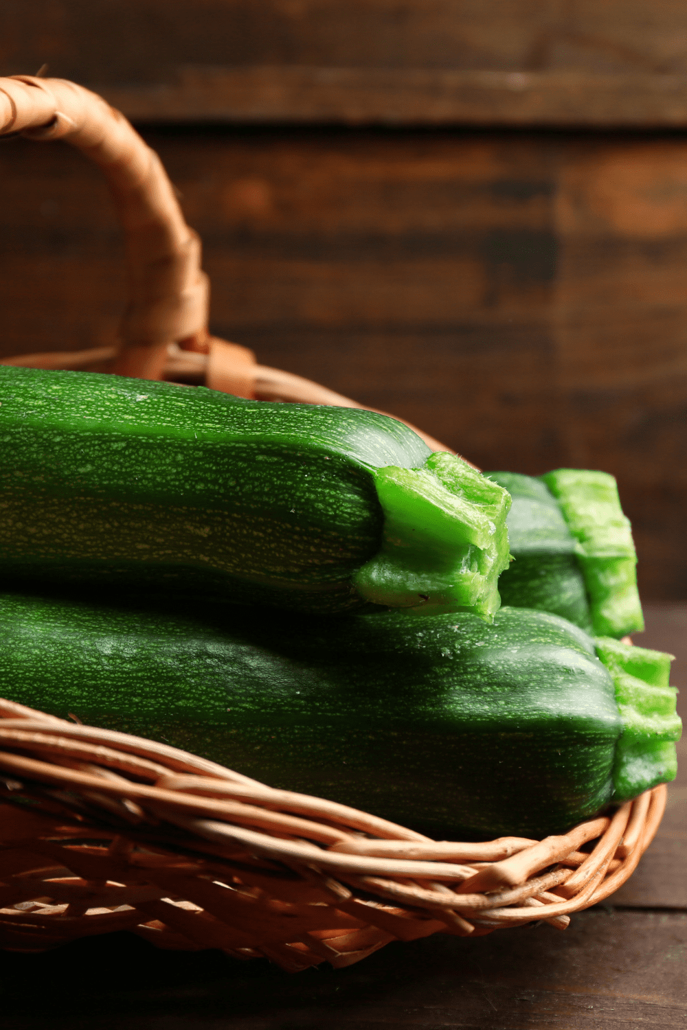 zucchini in wicker basket with wood in background