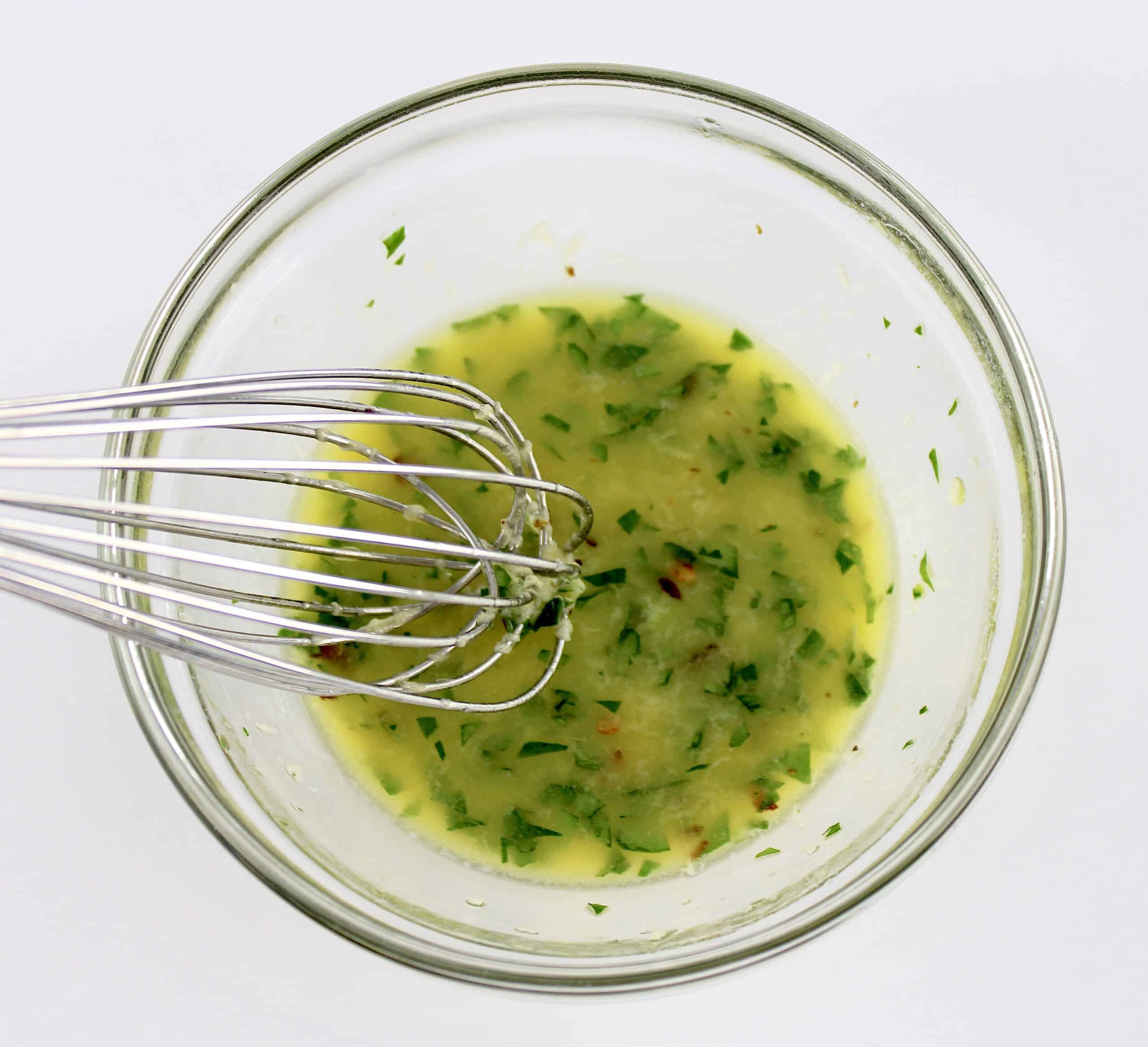 garlic herb butter in glass bowl with whisk