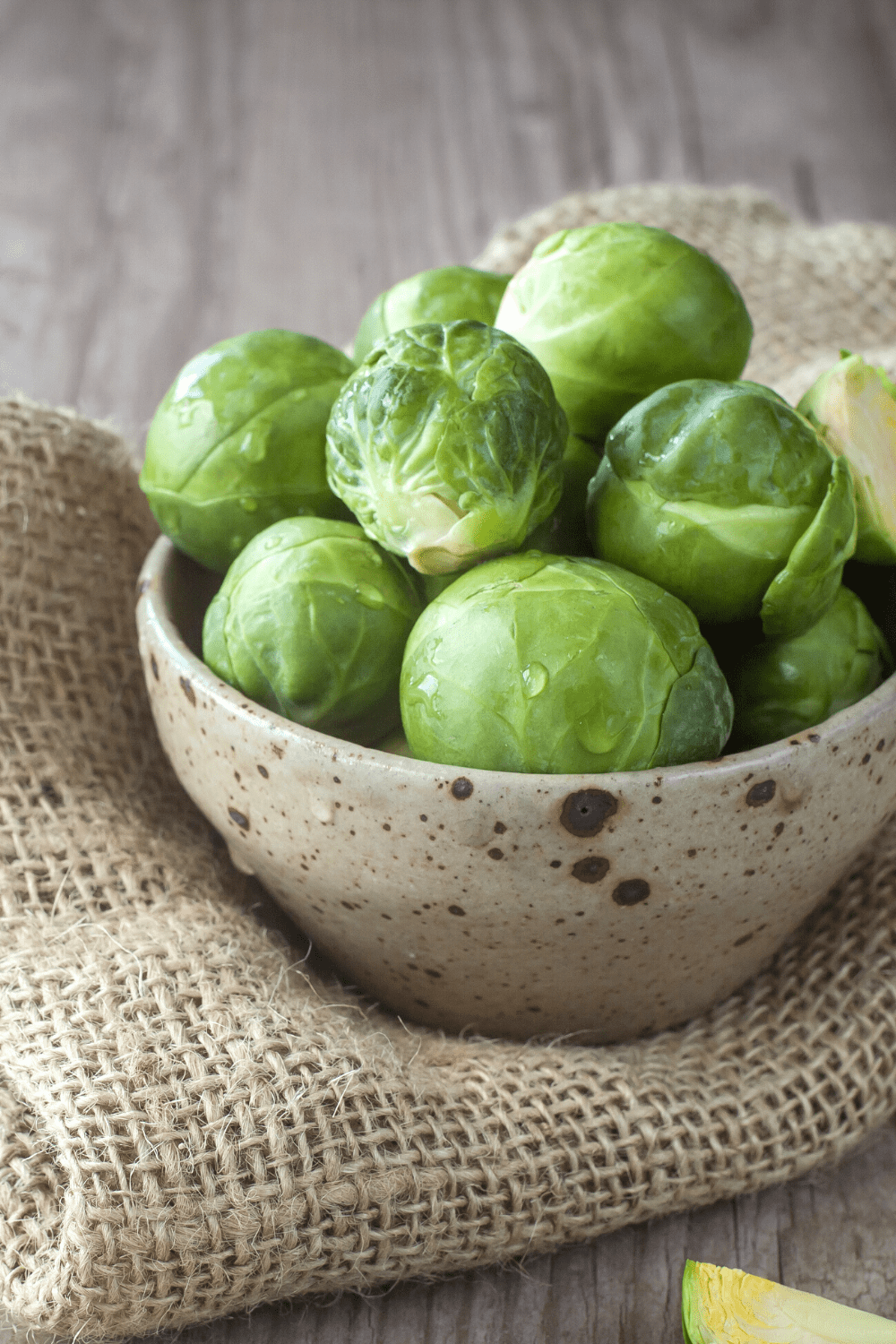 Brussels Sprouts in beige bowl sitting on burlap