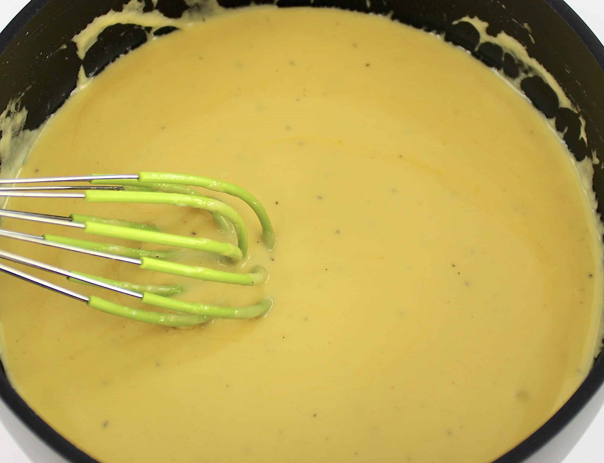 cauliflower mac and cheese sauce in saucepan with whisk