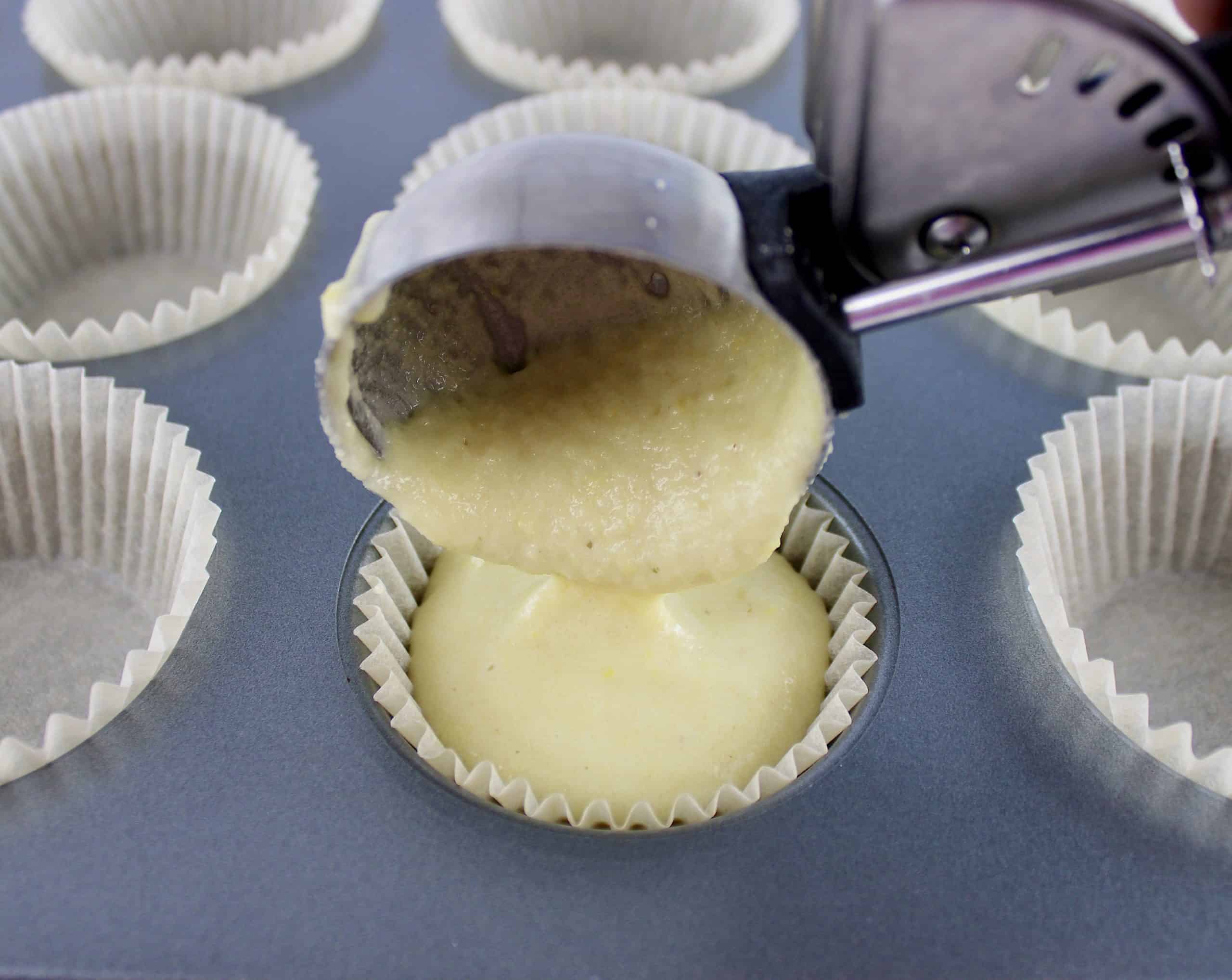 cupcake batter being poured into muffin liners in muffin pan