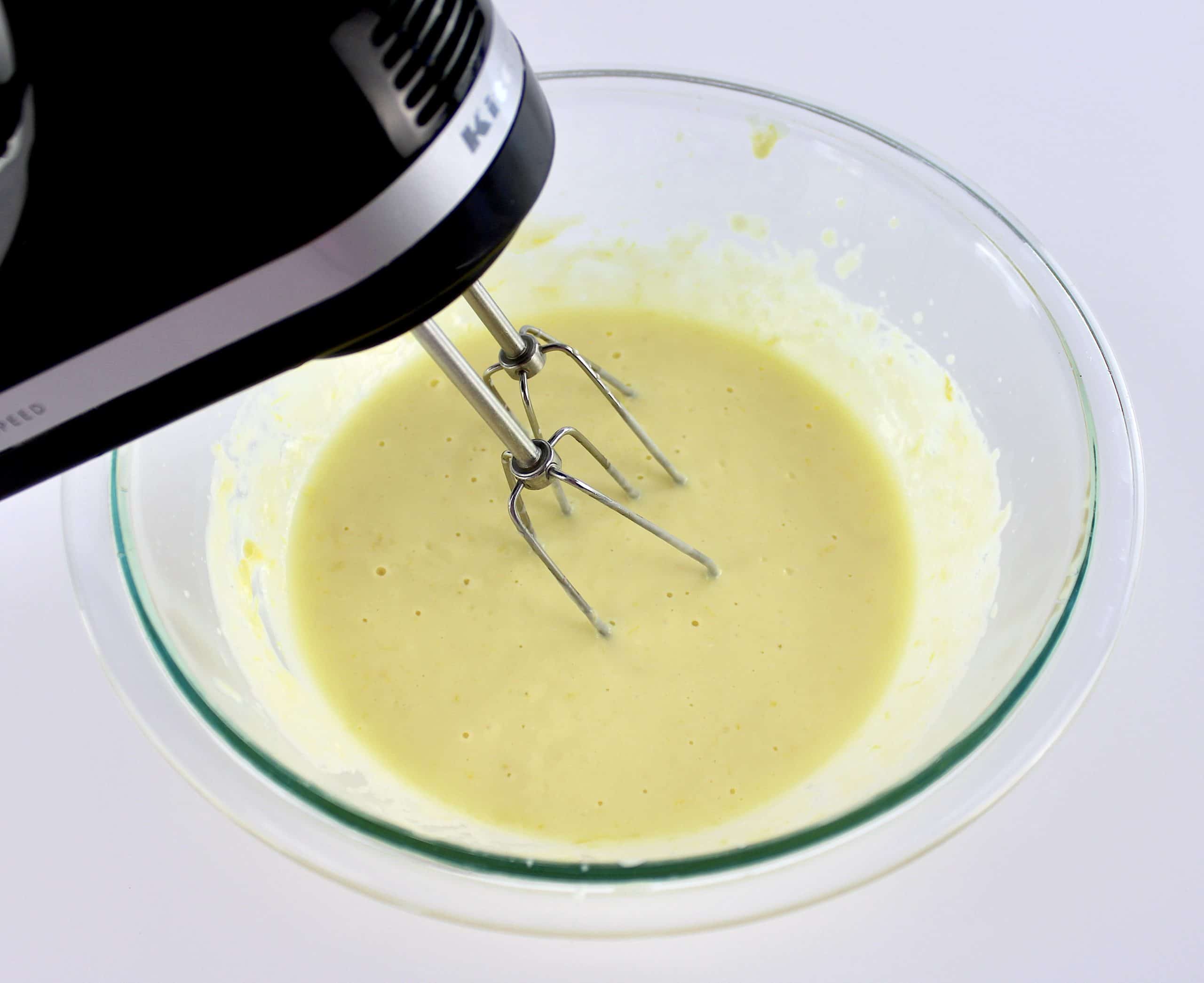 eggs and sweetener being mixed with hand mixer in glass bowl