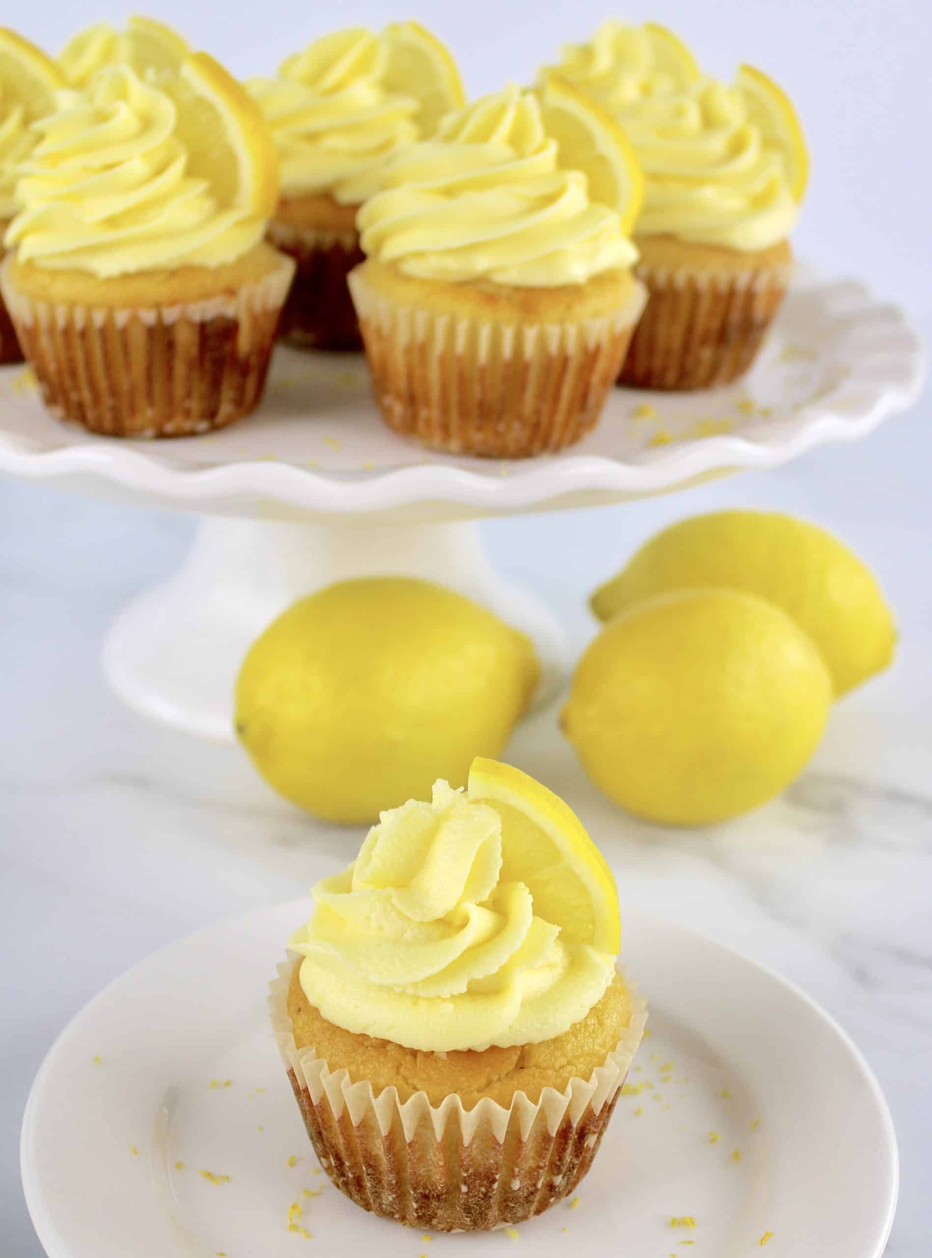lemon cupcakes on white stand with one cupcake on round white dish
