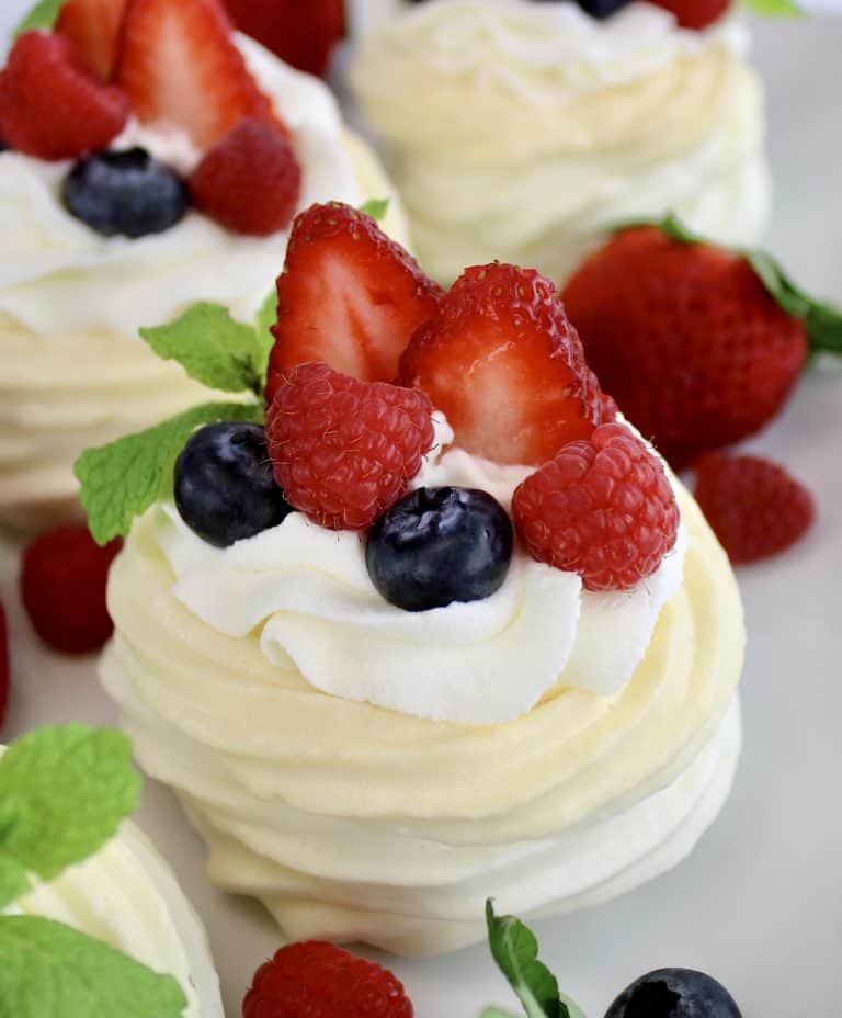 Mini Keto Pavlova with whip cream and a few berries with mint sprig on top