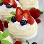Mini Keto Pavlova with whip cream and a few berries with mint sprig on top