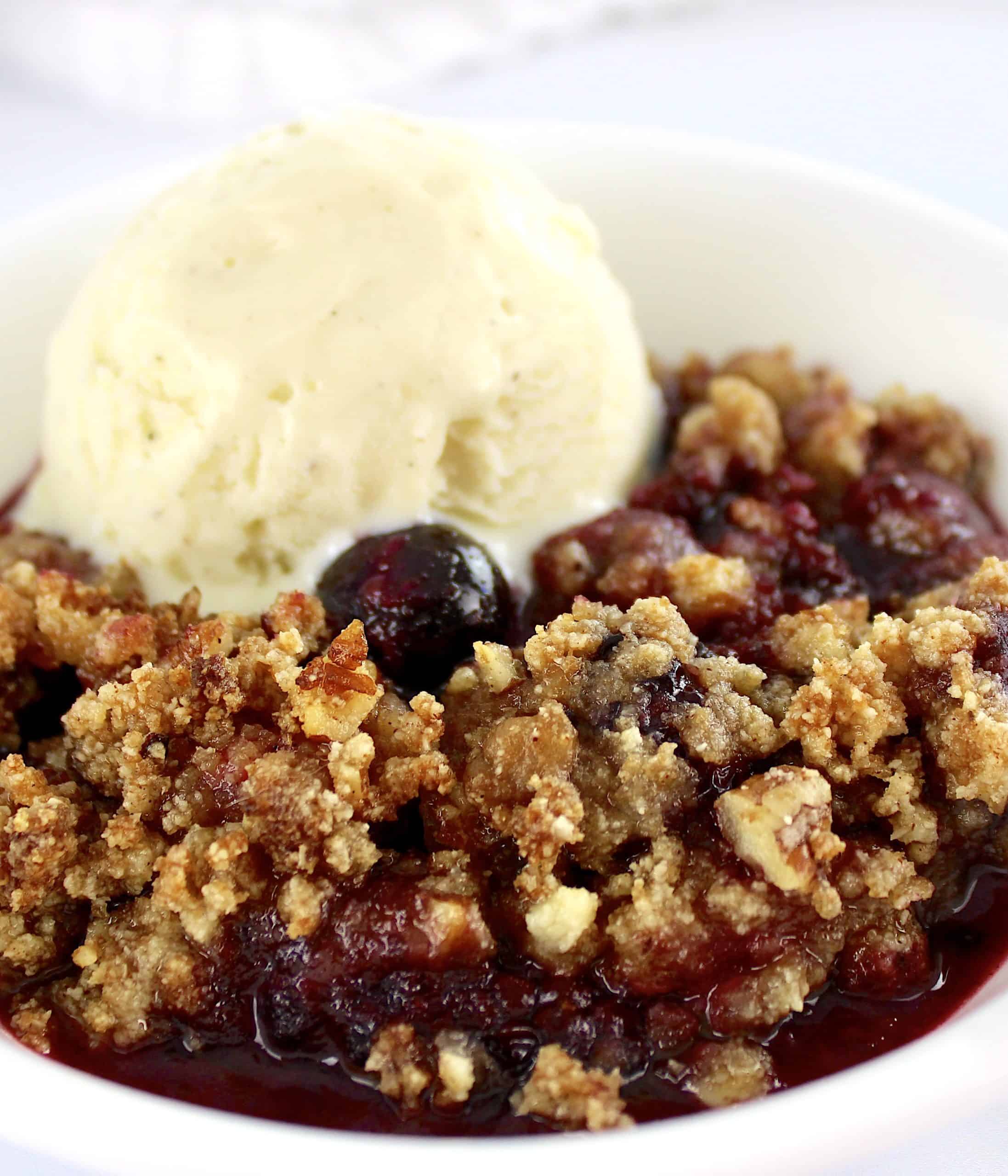 closeup of Mixed Berry Crumble in white bowl with scoop of vanilla ice cream