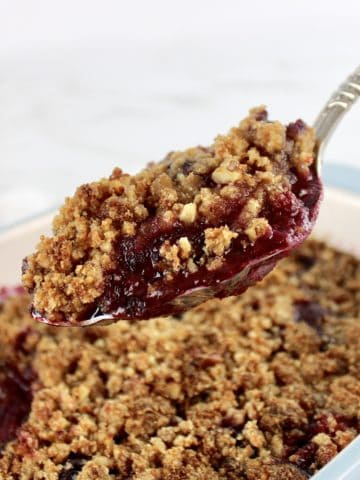 scoop of Mixed Berry Crumble held up over casserole