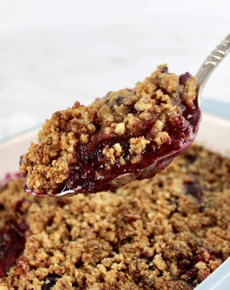 scoop of Mixed Berry Crumble held up over casserole