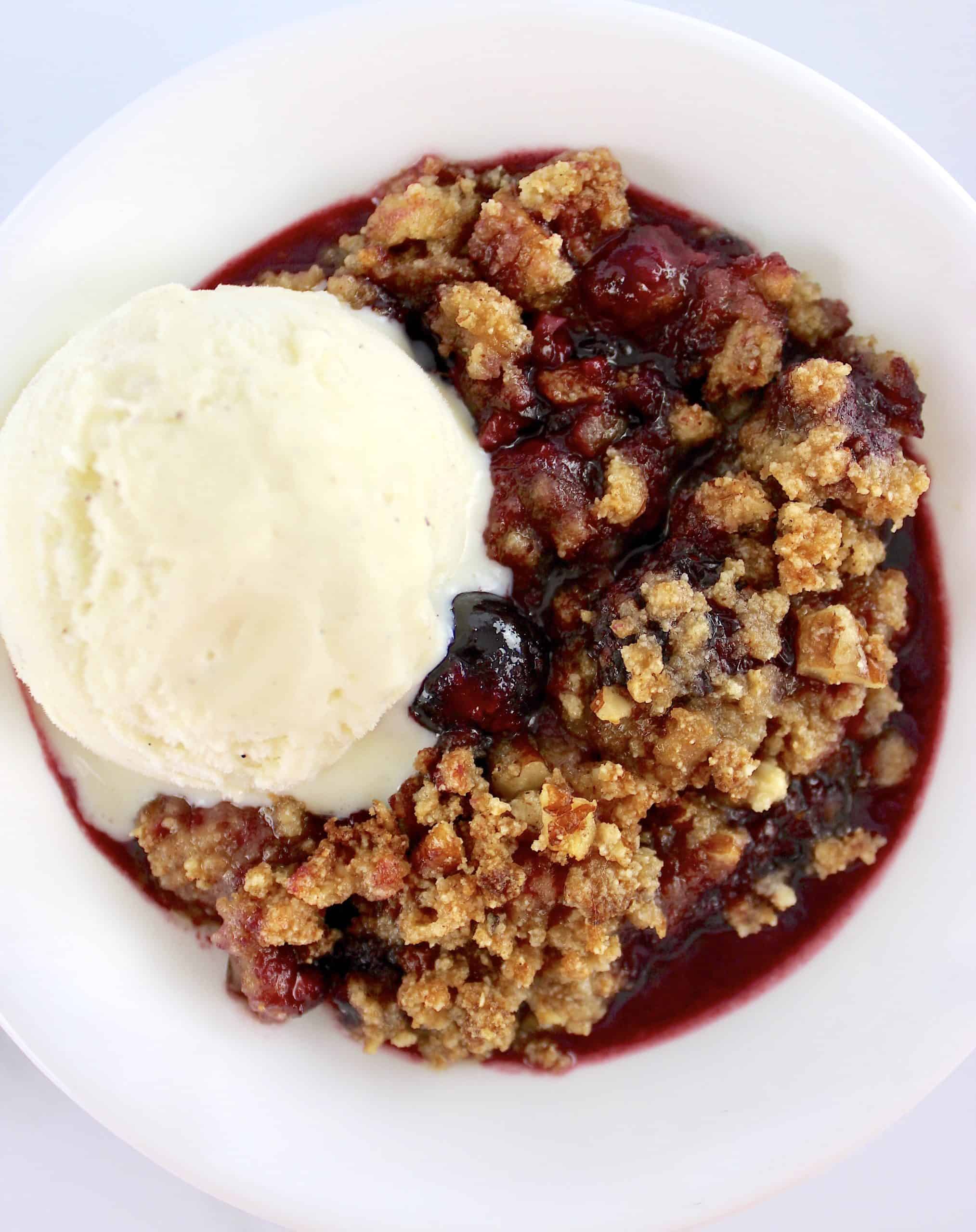 overhead view of Mixed Berry Crumble in white bowl with scoop of vanilla ice cream