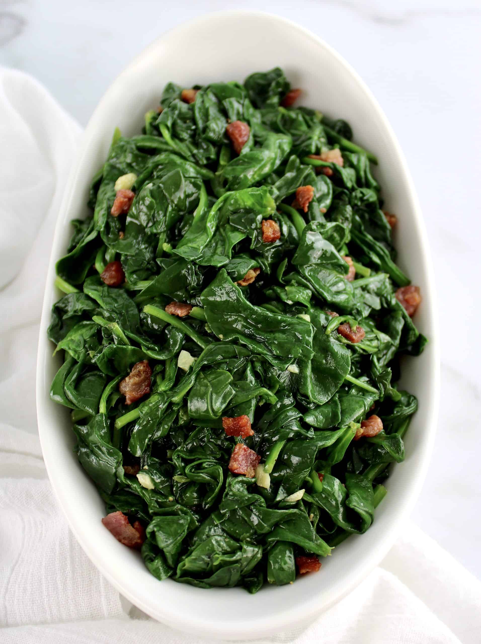 overhead view of Sautéed Spinach with Pancetta in white bowl