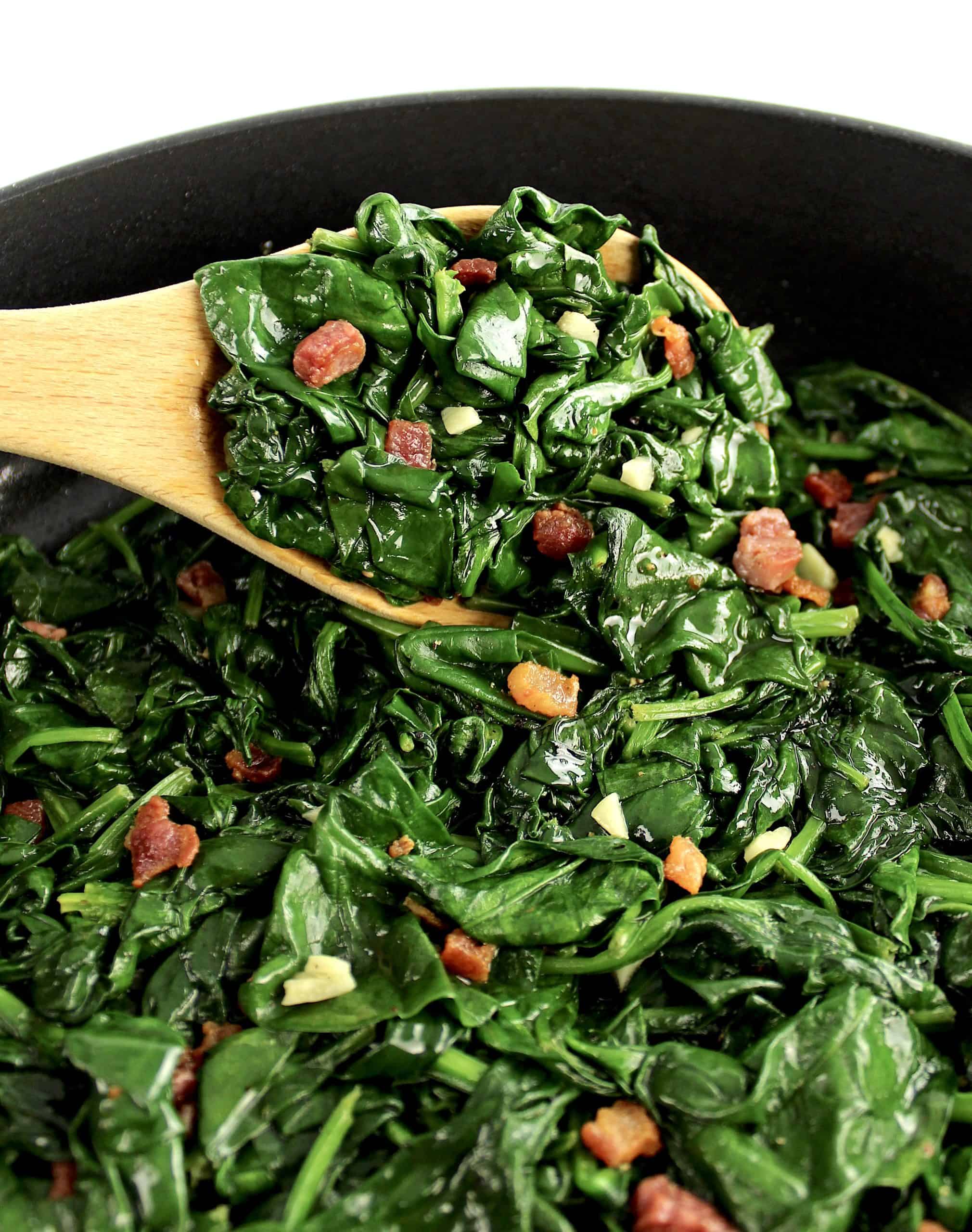 Sautéed Spinach with Pancetta with wooden spoon holding up some