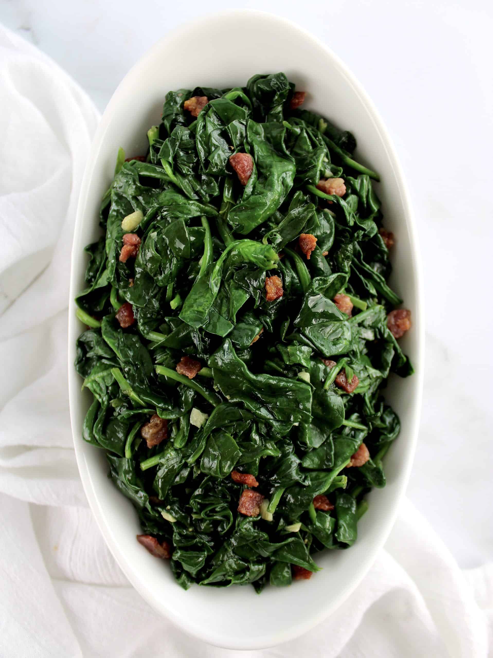 overhead view of Sautéed Spinach with Pancetta in white bowl