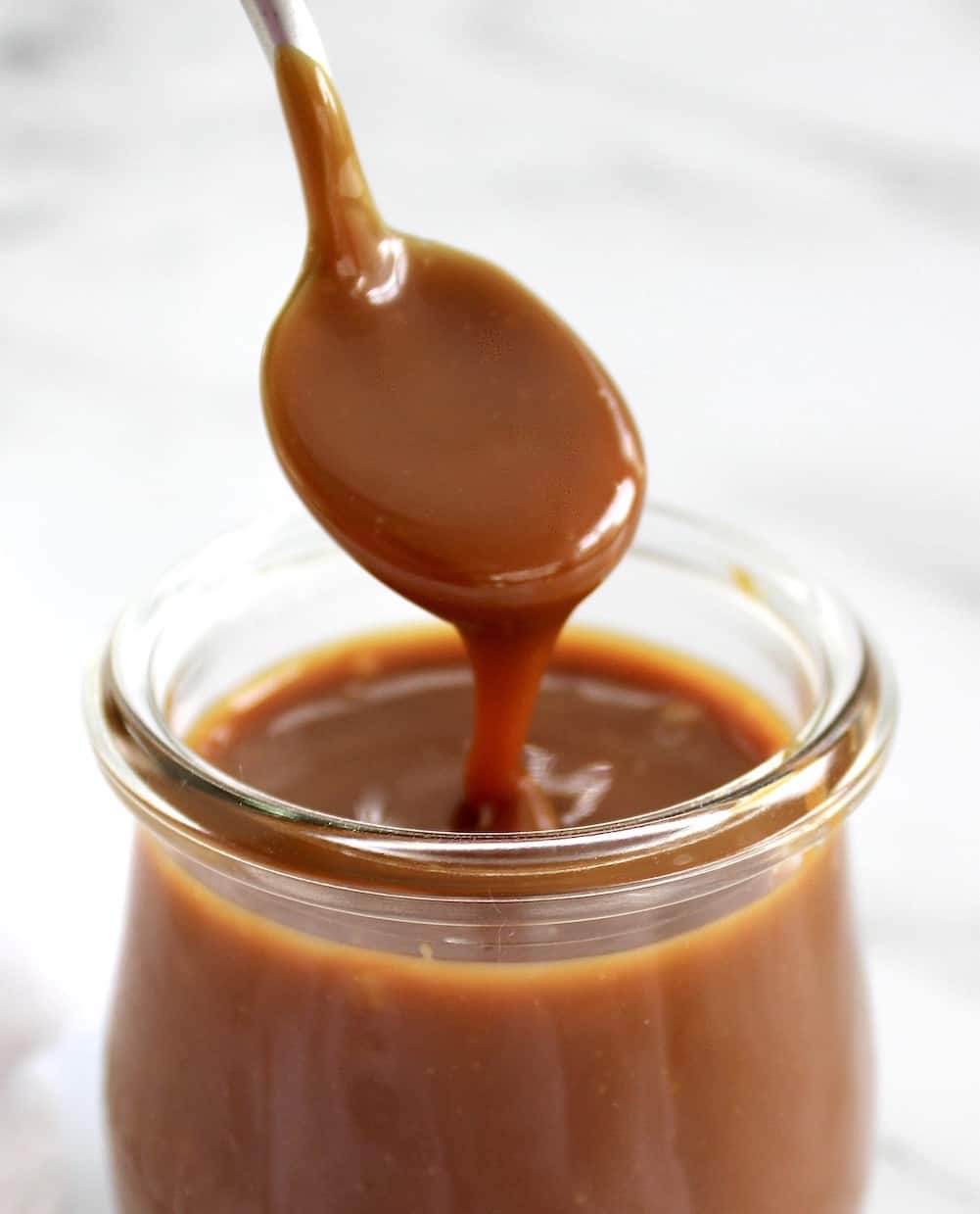 salted caramel sauce being spooned out of jar