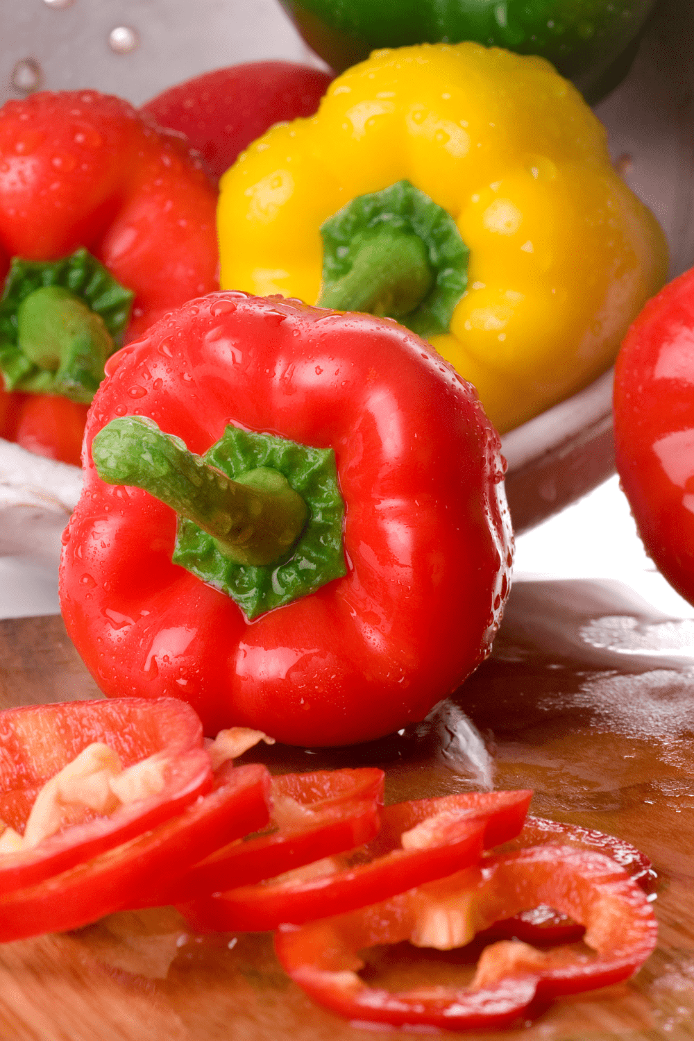 red and yellow bell peppers being poured out of colander onto cutting board